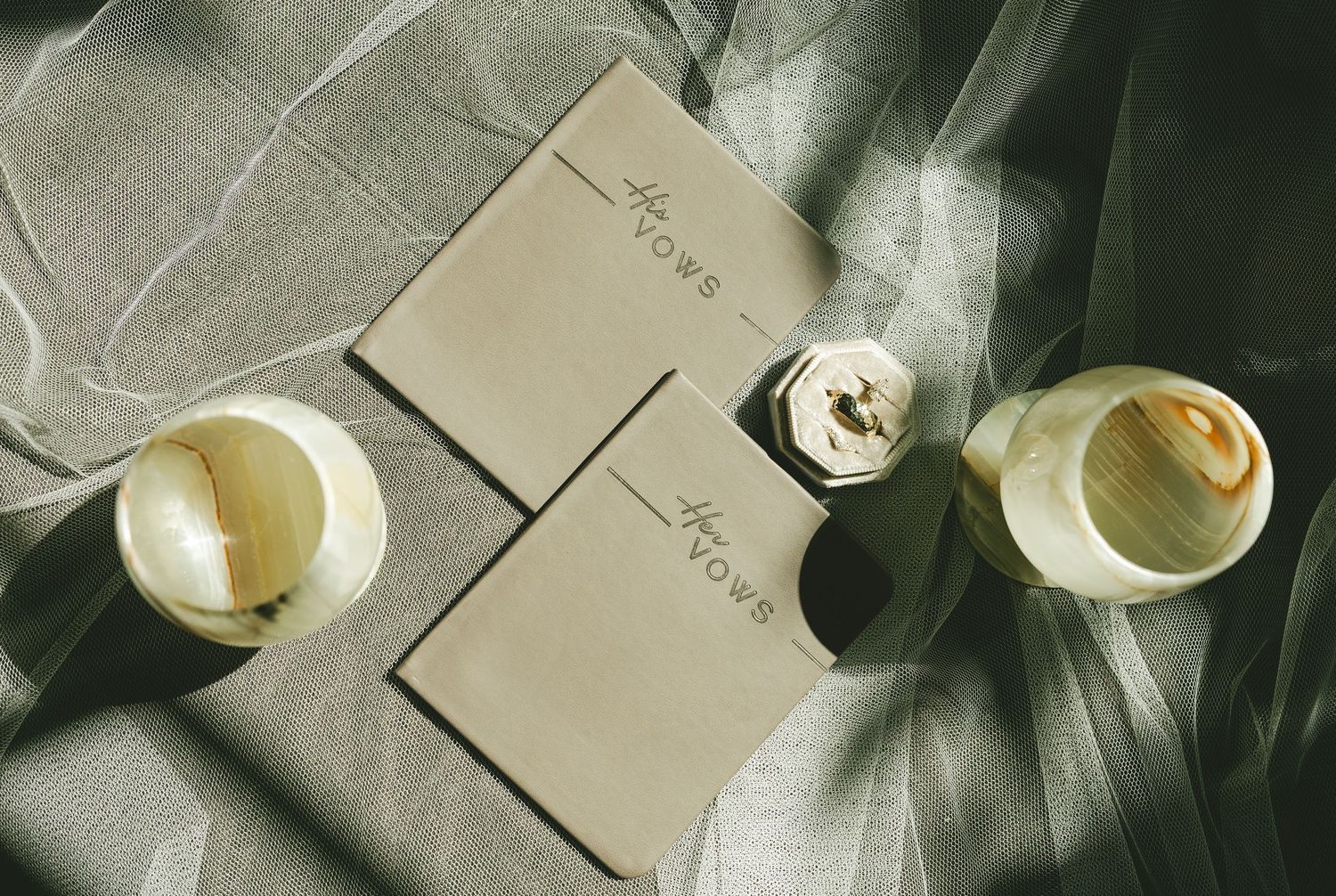 Top view of two beige notebooks with coffee cups on gray fabric creating soft shadows.