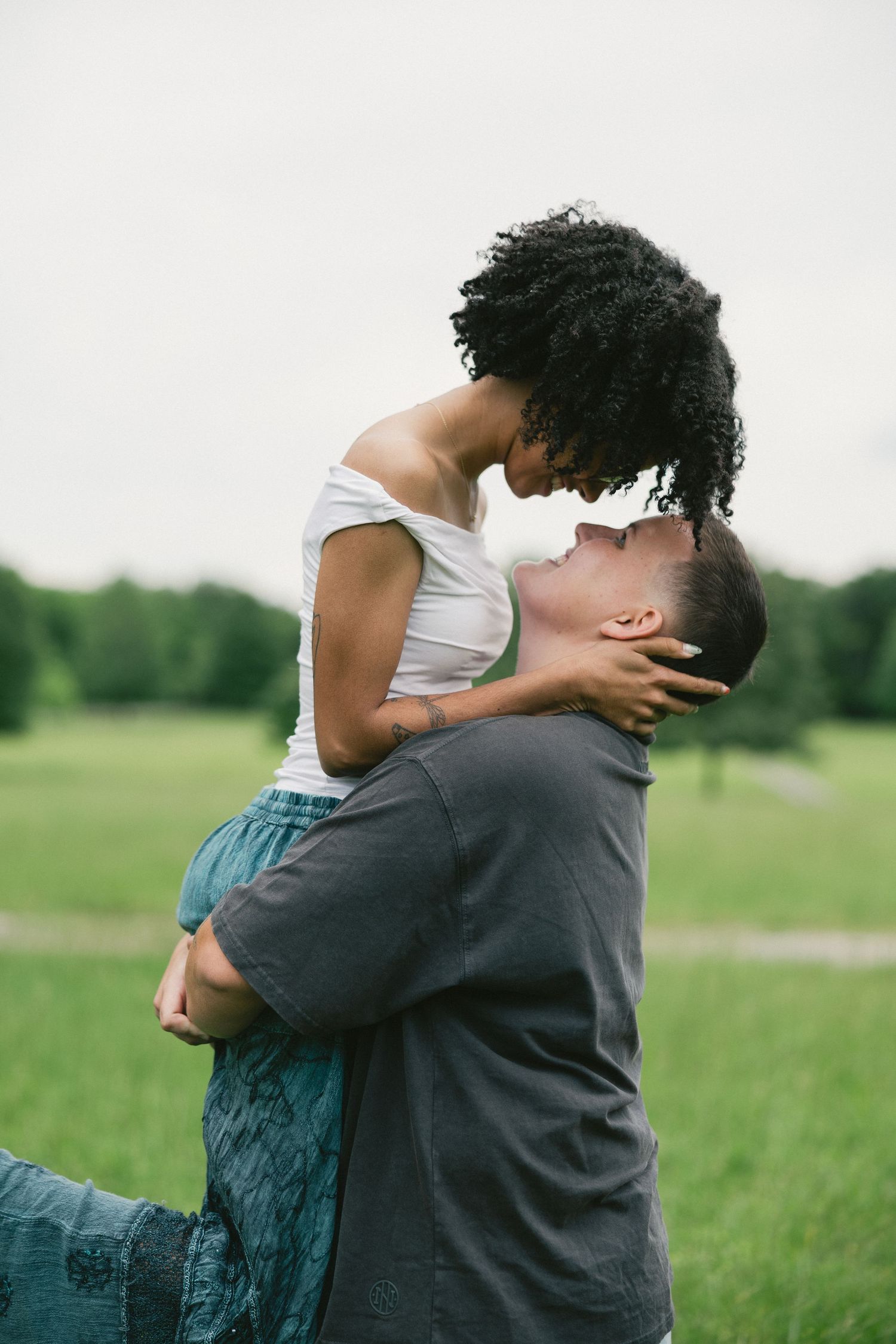 Couple embracing in a grassy field showing tender affection through romantic poses.