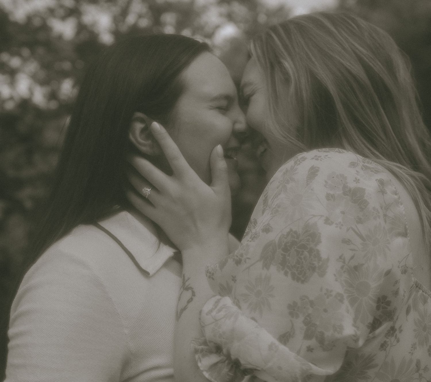 A tender intimate moment between two people sharing a gentle embrace in a soft black and white photograph.