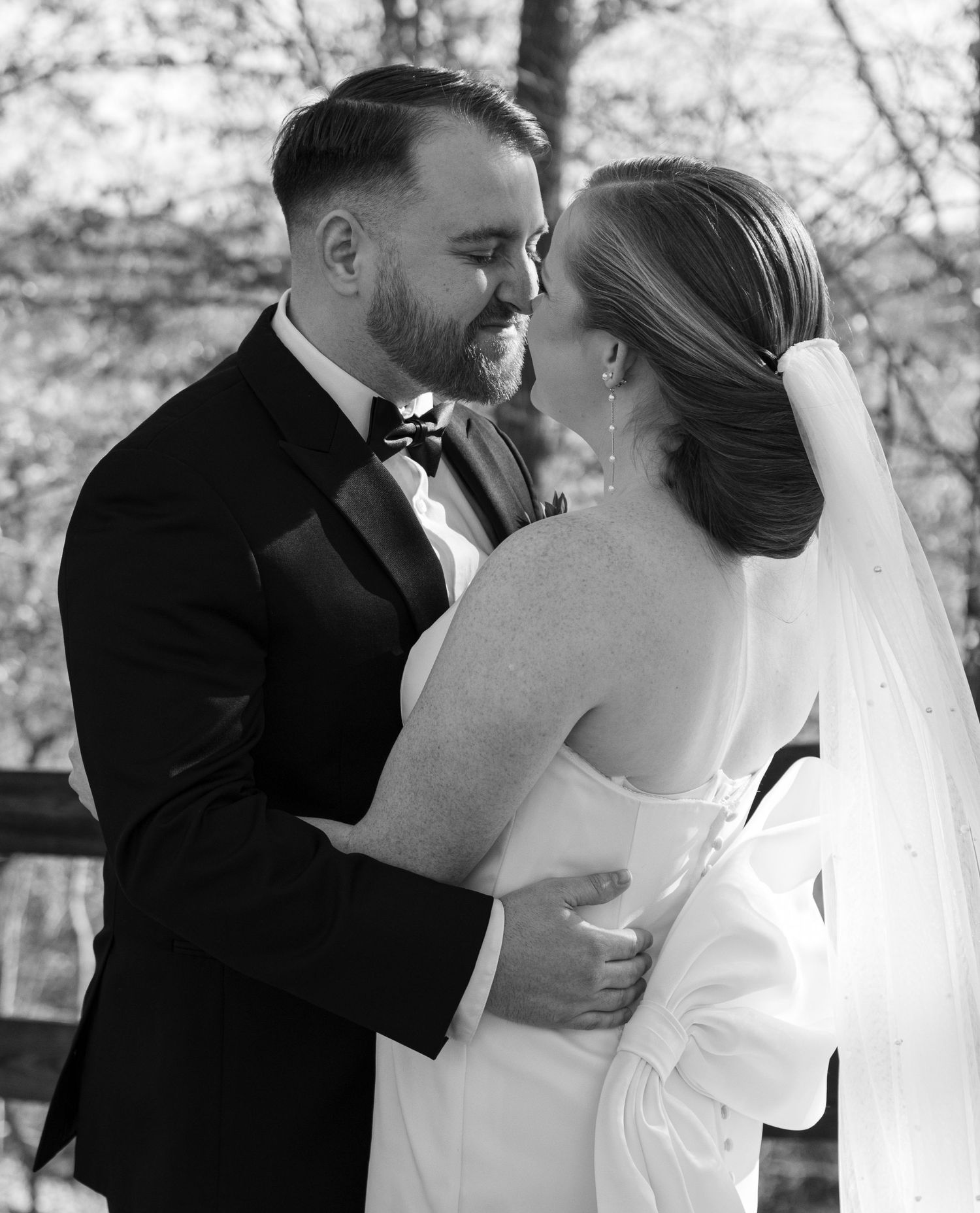 A romantic black and white candid photograph of a newlywed couple sharing an intimate moment during their wedding.