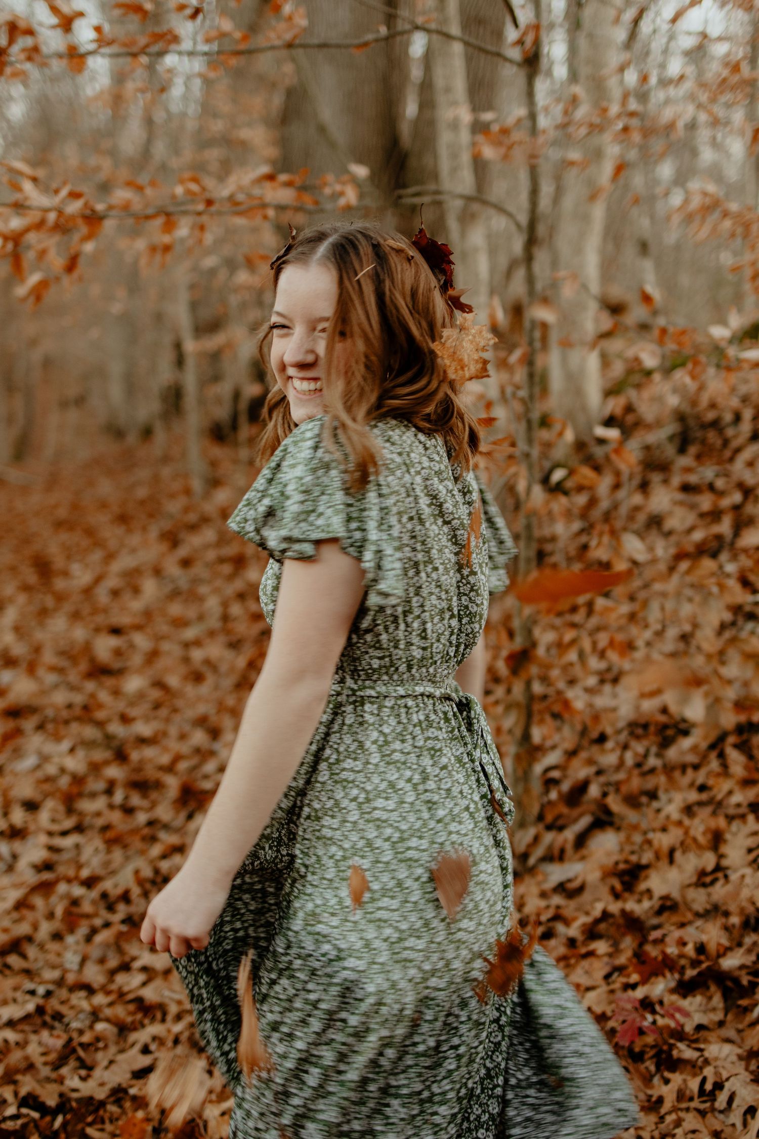 Four sequential photos showing someone in a floral dress spinning joyfully among autumn trees and fallen leaves.