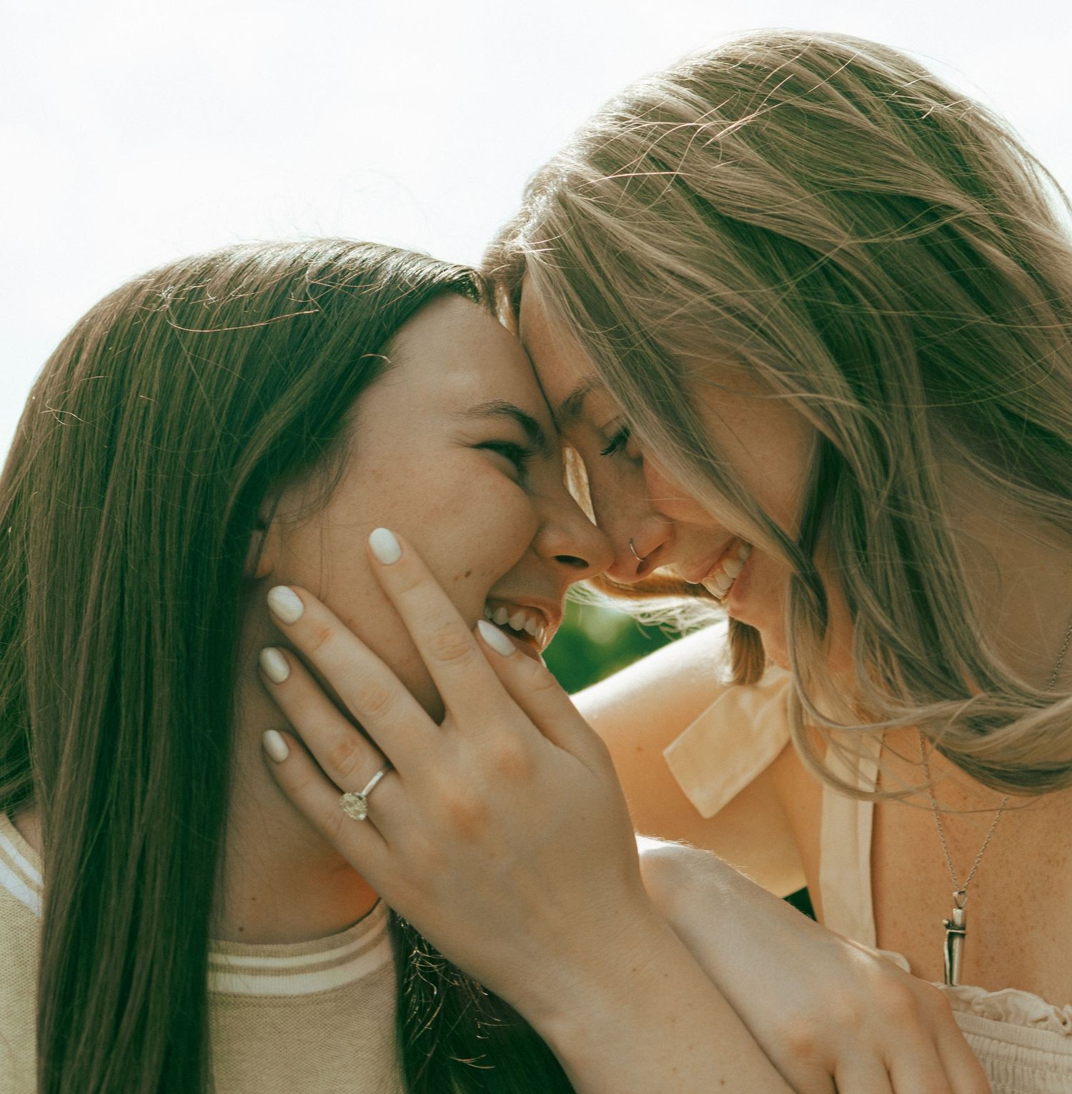 Two people sharing an intimate laughing moment together in warm sunlight.