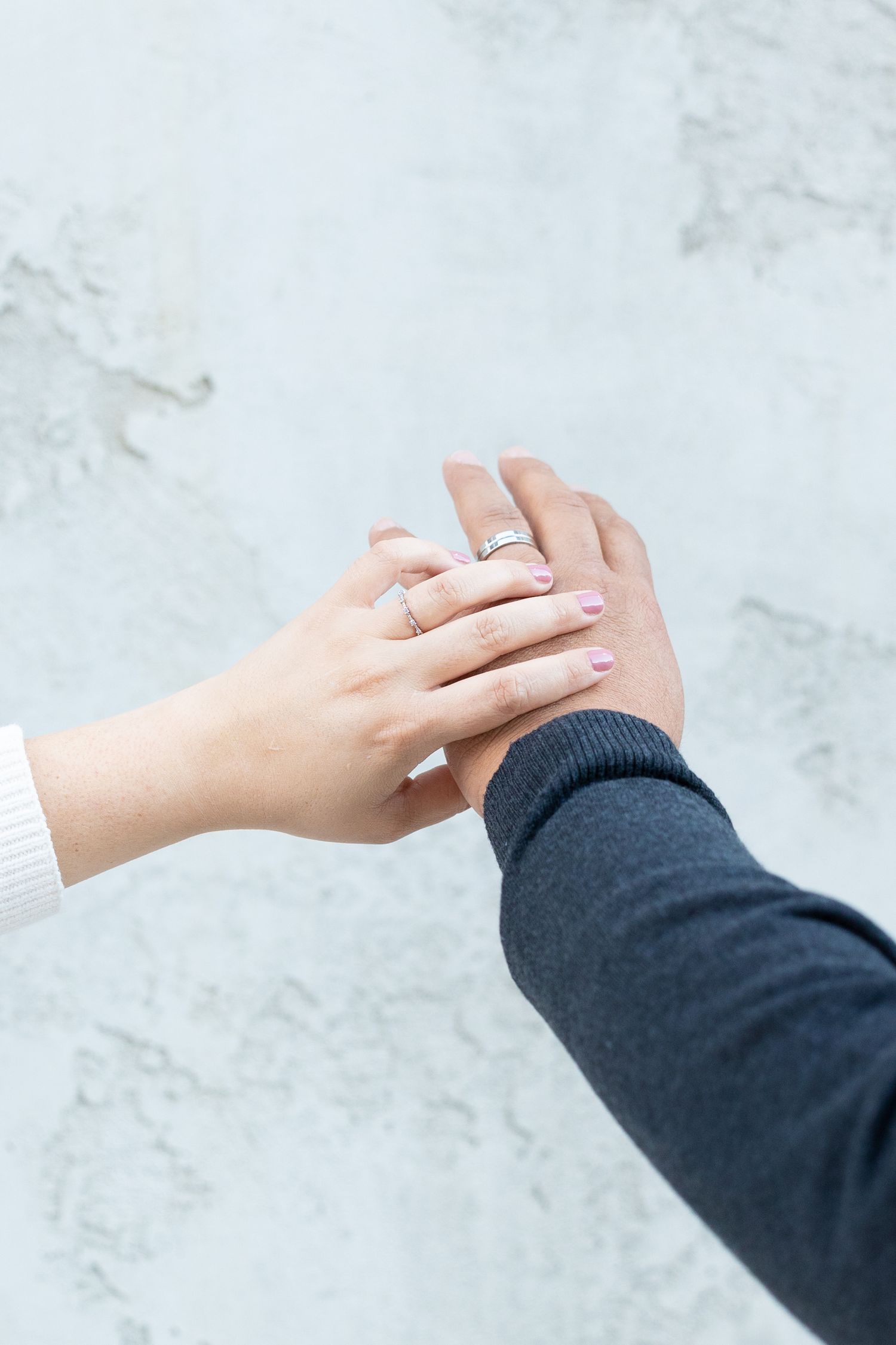 Couple holding their hands together showing their engagement rings