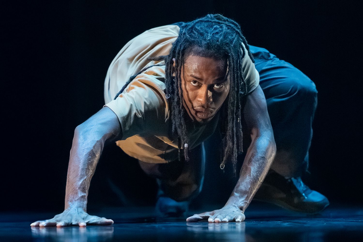 Performer doing push-up poses in dramatic lighting during an artistic dance performance.