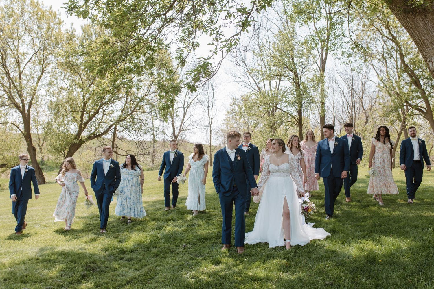 Wedding party walks through scenic orchard as they celebrate the newlyweds' special day.