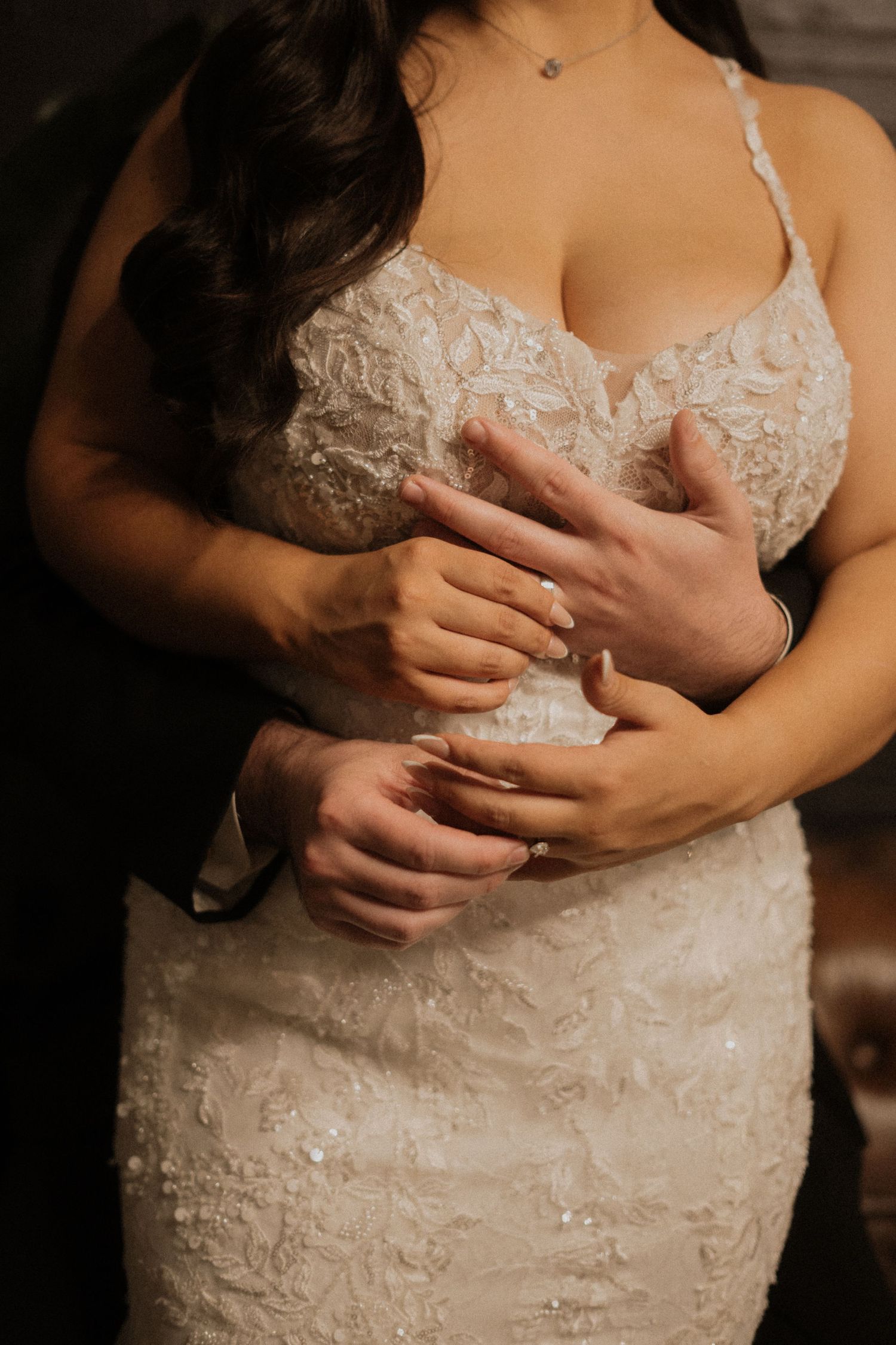 Close-up detail of an intricate white lace wedding dress bodice with delicate embellishments.