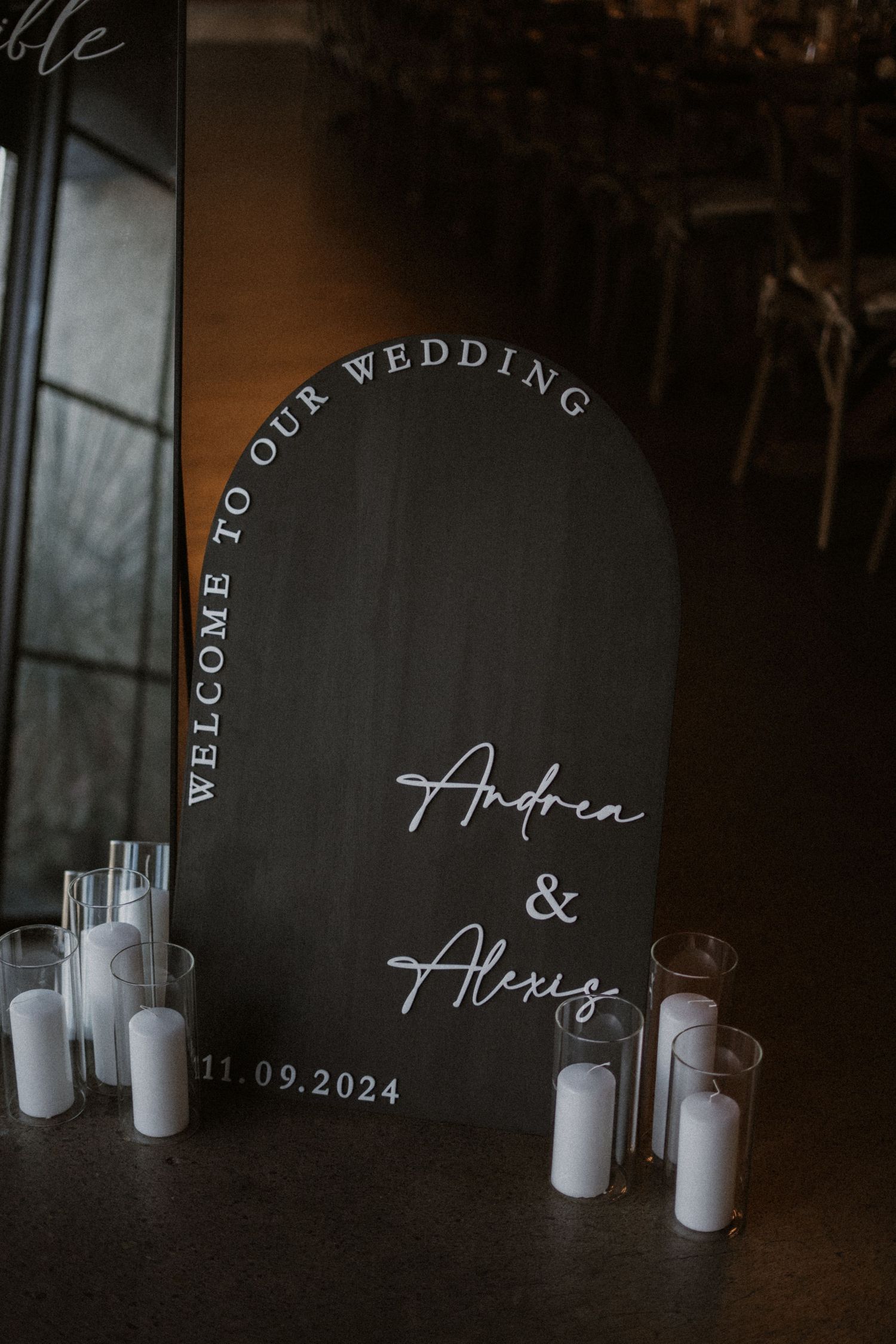 Black circular wedding welcome sign with white text and candle decorations.
