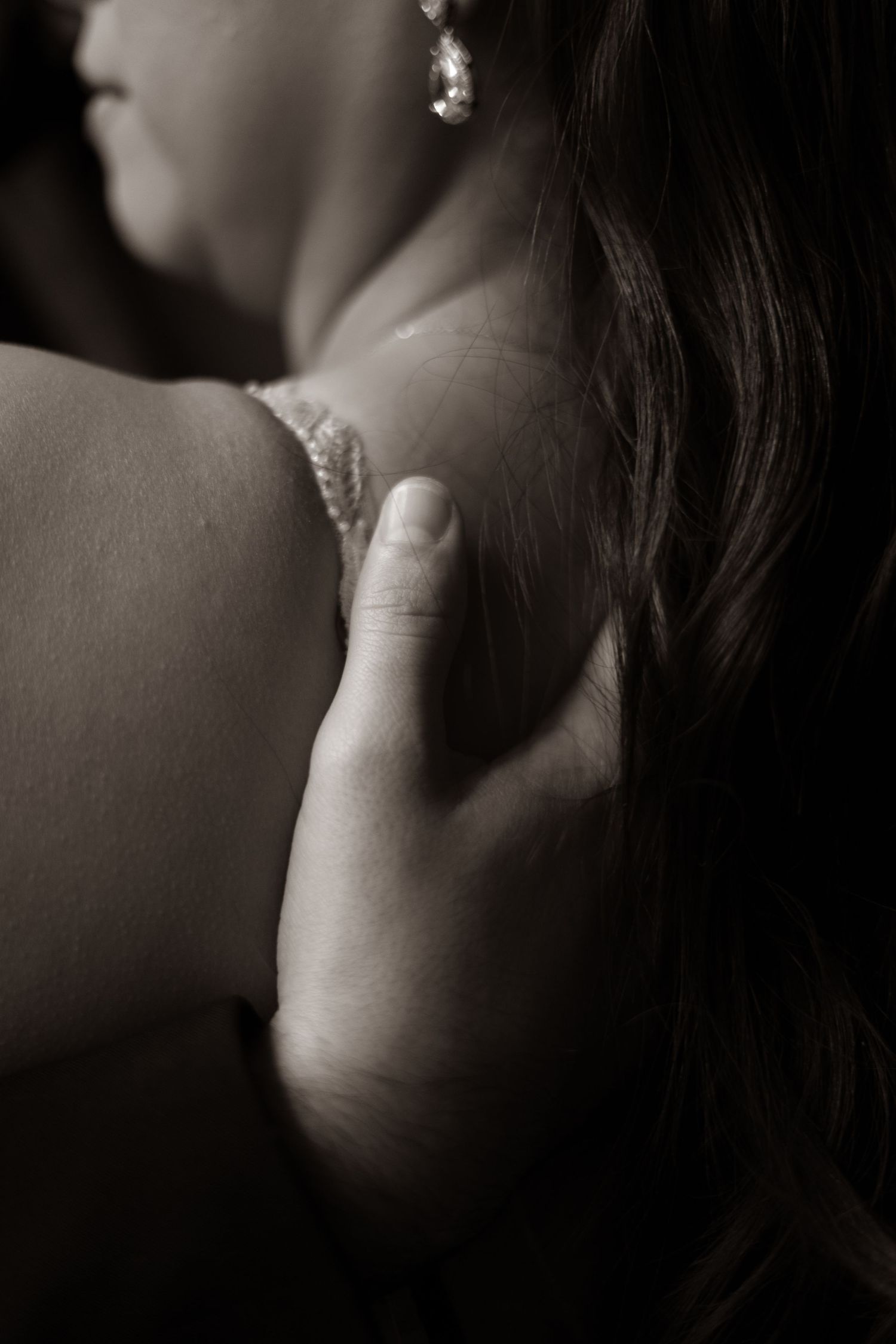 Artistic black and white close-up showing wedding day jewelry and bare shoulders.