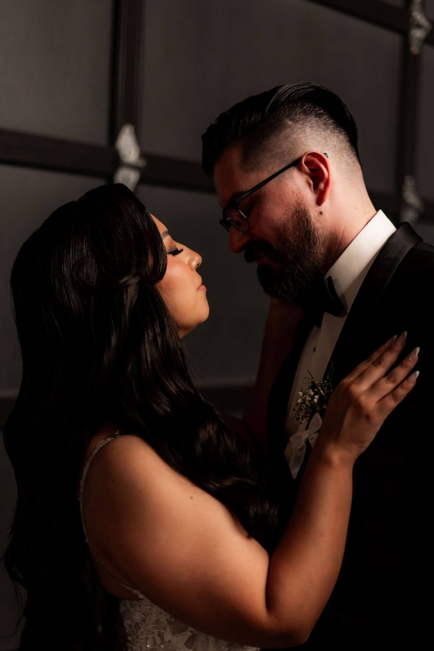 Candid wedding photo showing a tender embrace in dramatic lighting.