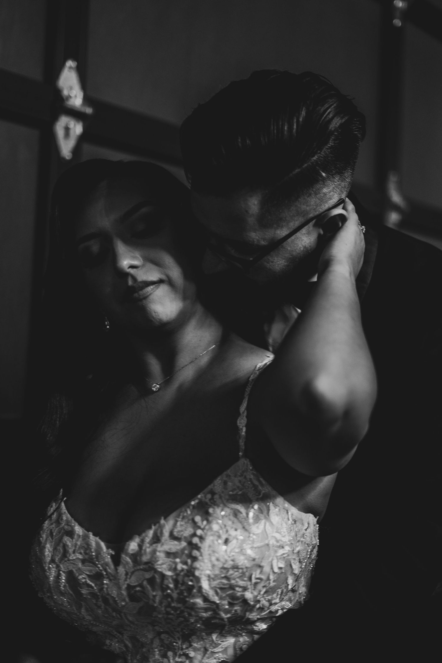 Dramatic shadows and light capture details of a lace wedding dress in black and white.