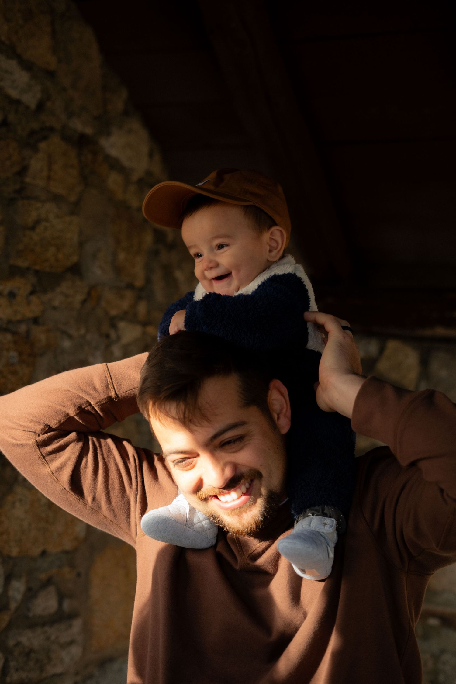 Intimate family moment captured in warm lighting against stone wall backdrop.