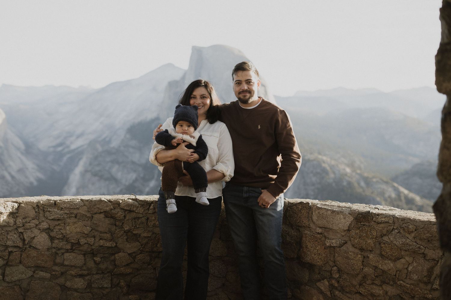 Group poses together at mountain viewpoint during sunset with Half Dome visible in background.