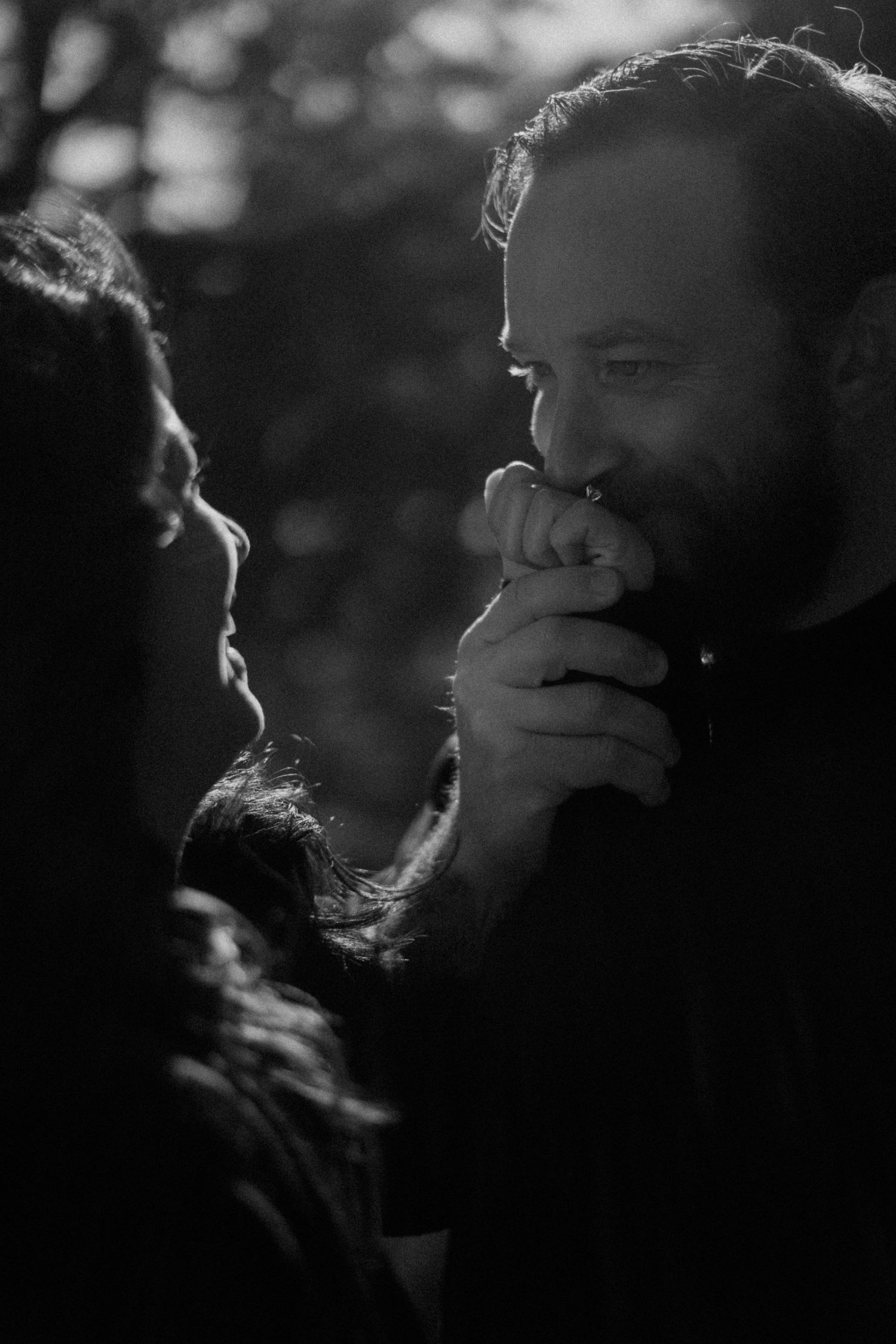A black and white close-up of a couple sharing a tender moment outdoors.