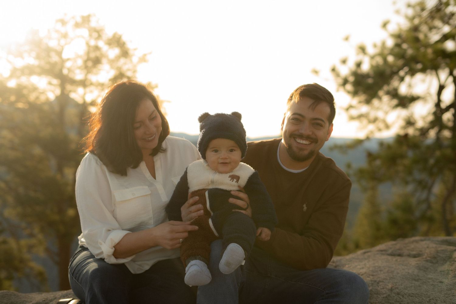 Family enjoying sunset moment together on rocky mountain overlook.