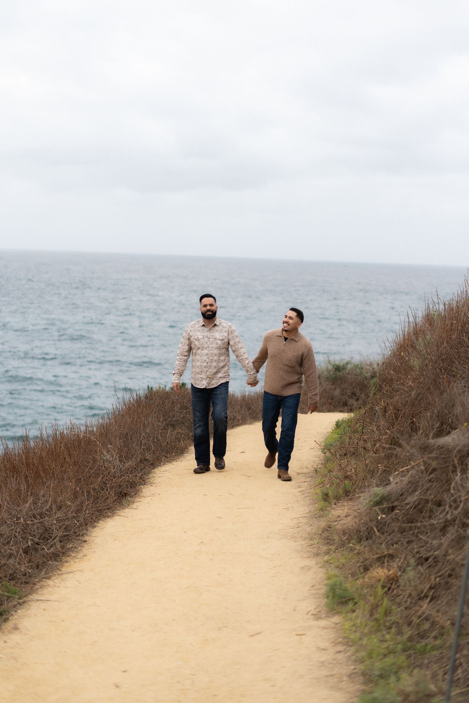 Two people walking together on coastal trail with ocean view.