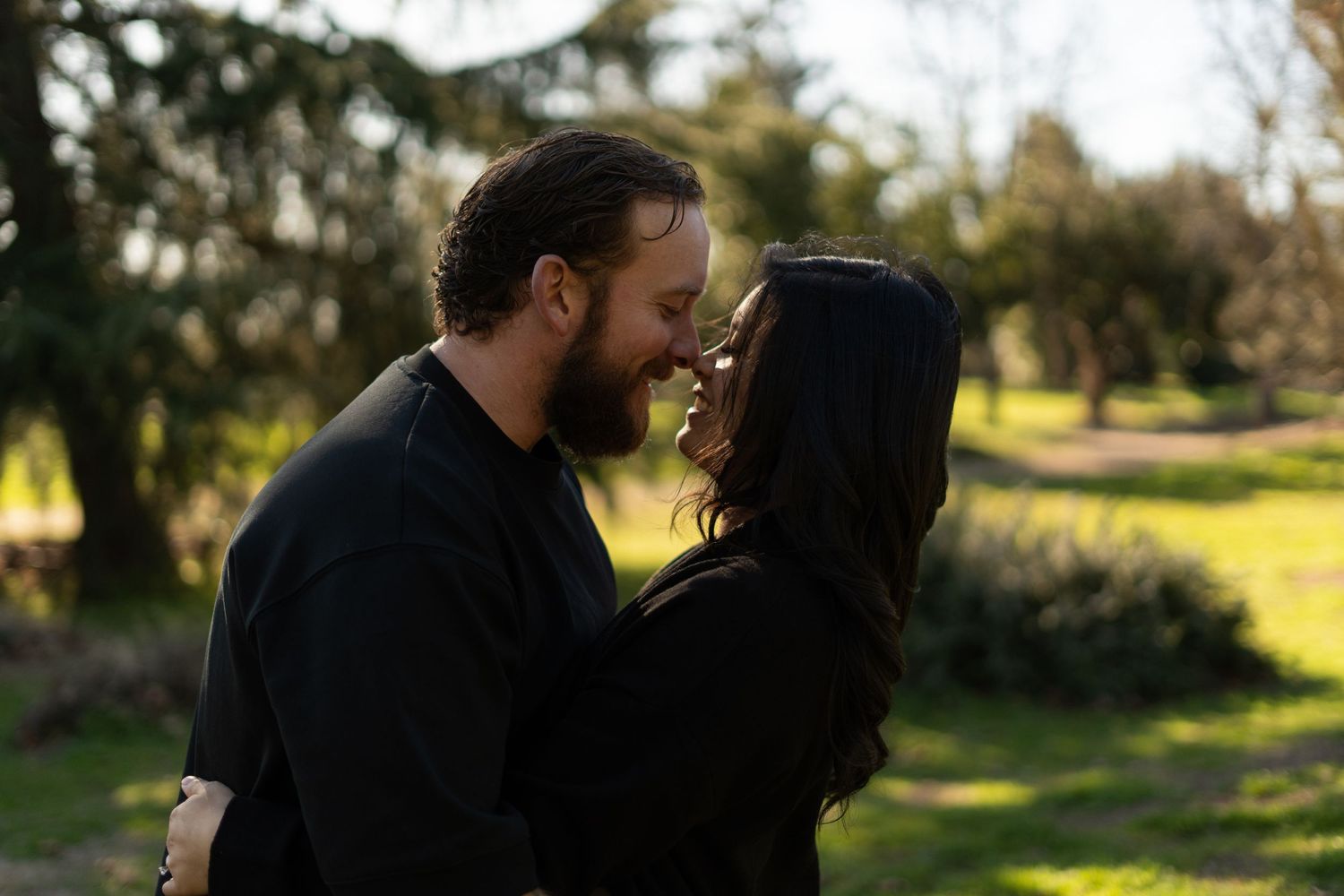 Candid couple's photography in a park with golden sunlight filtering through trees.