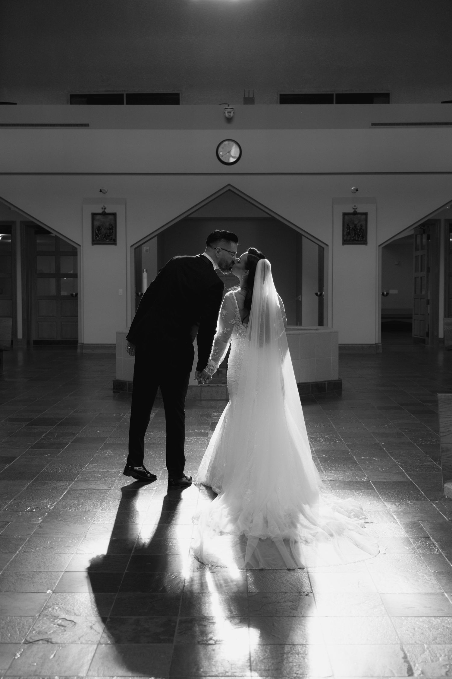 Dramatic black and white shots of a couple's silhouettes in a church with spotlighting.