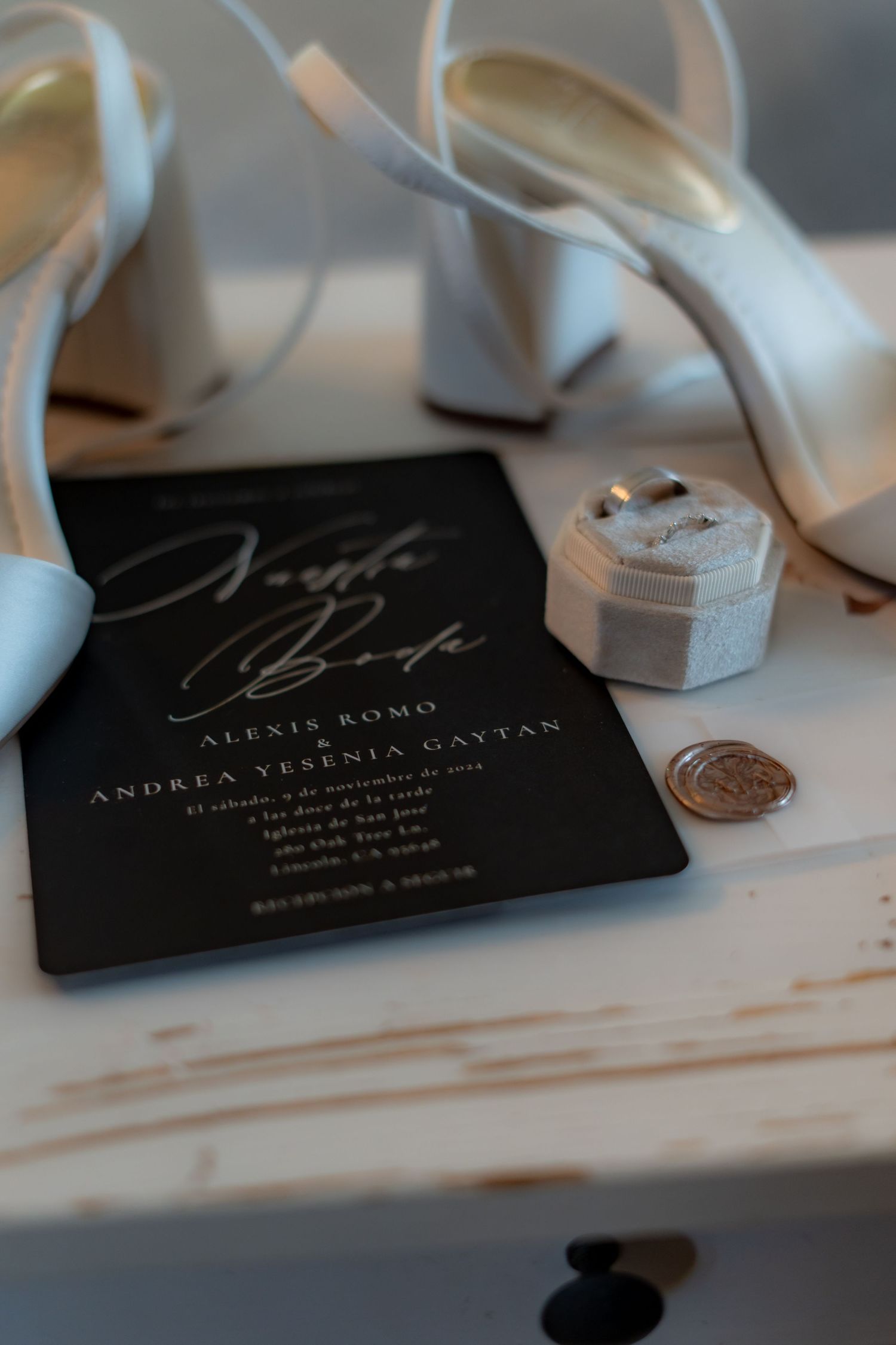 Elegant black wedding invitations with white ribbon and wax seals on marble surface.