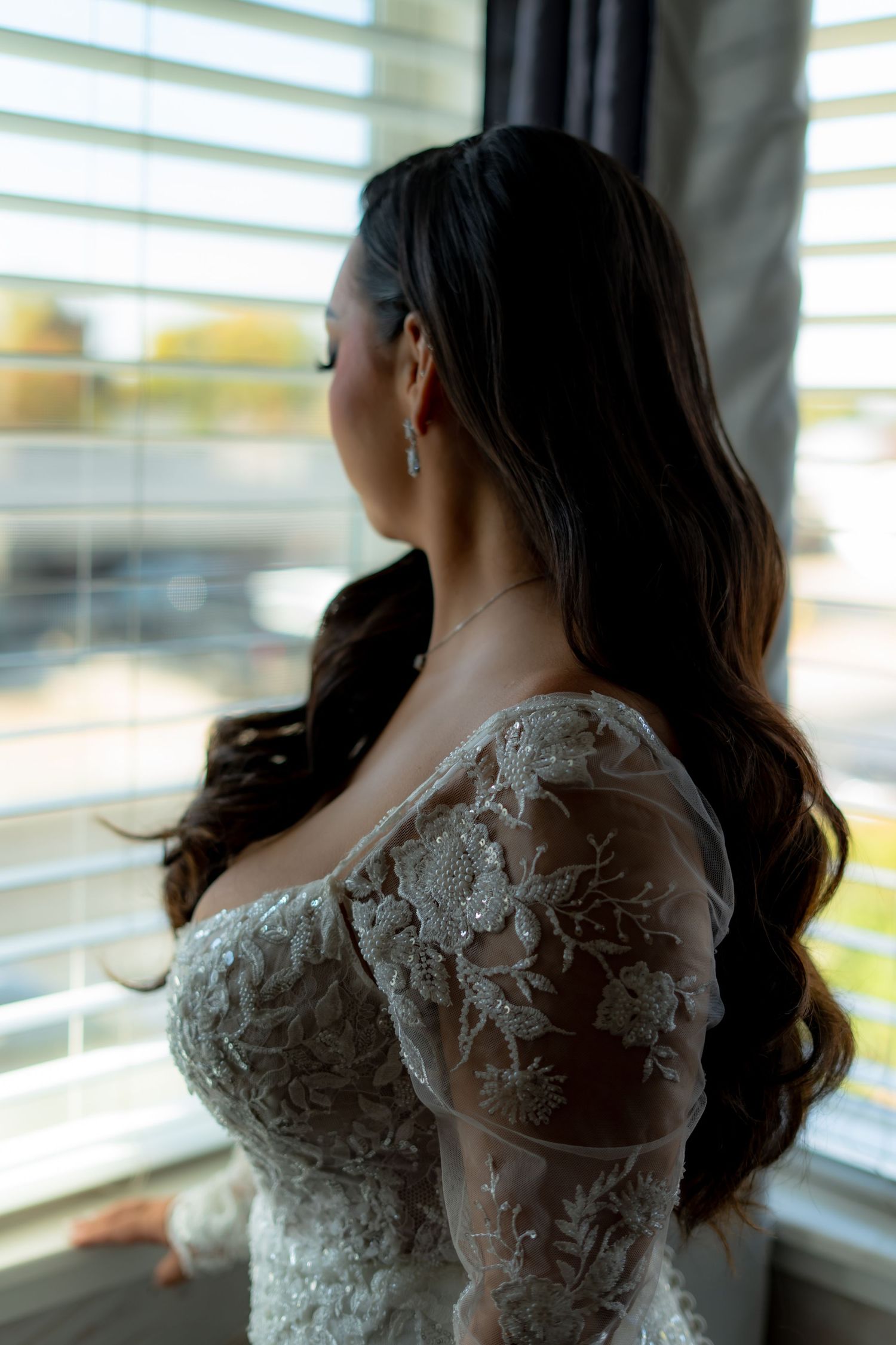 Close-up of delicate lace details on wedding dress by window.