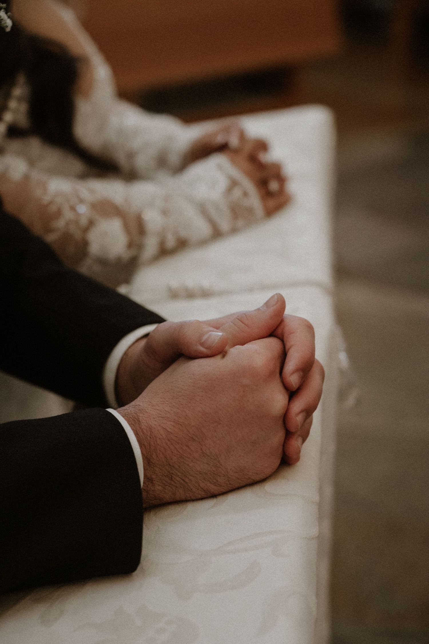 Close-up of clasped hands during intimate wedding ceremony moment.