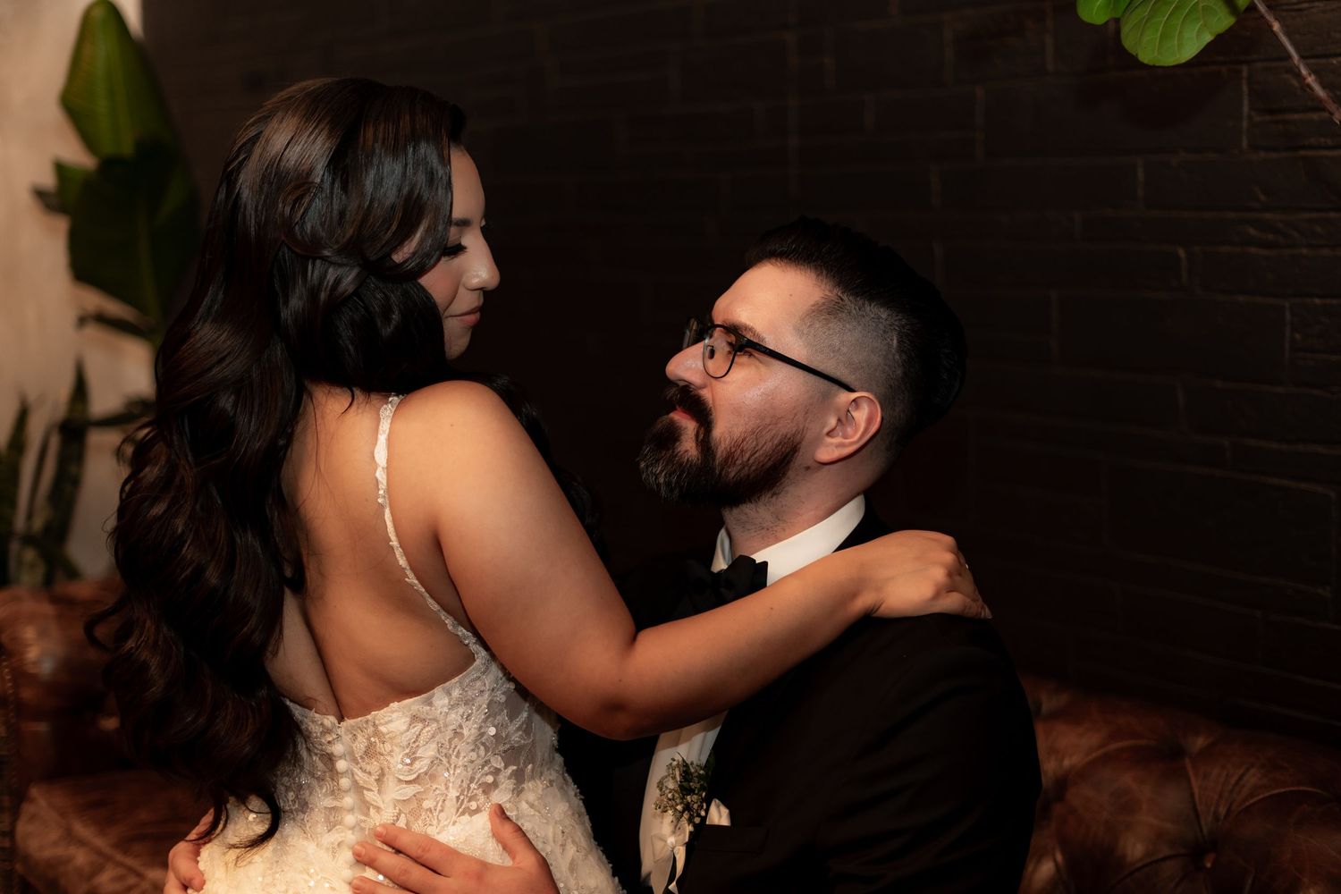 Wedding couple sharing an intimate dance moment in moody lighting against a dark background.