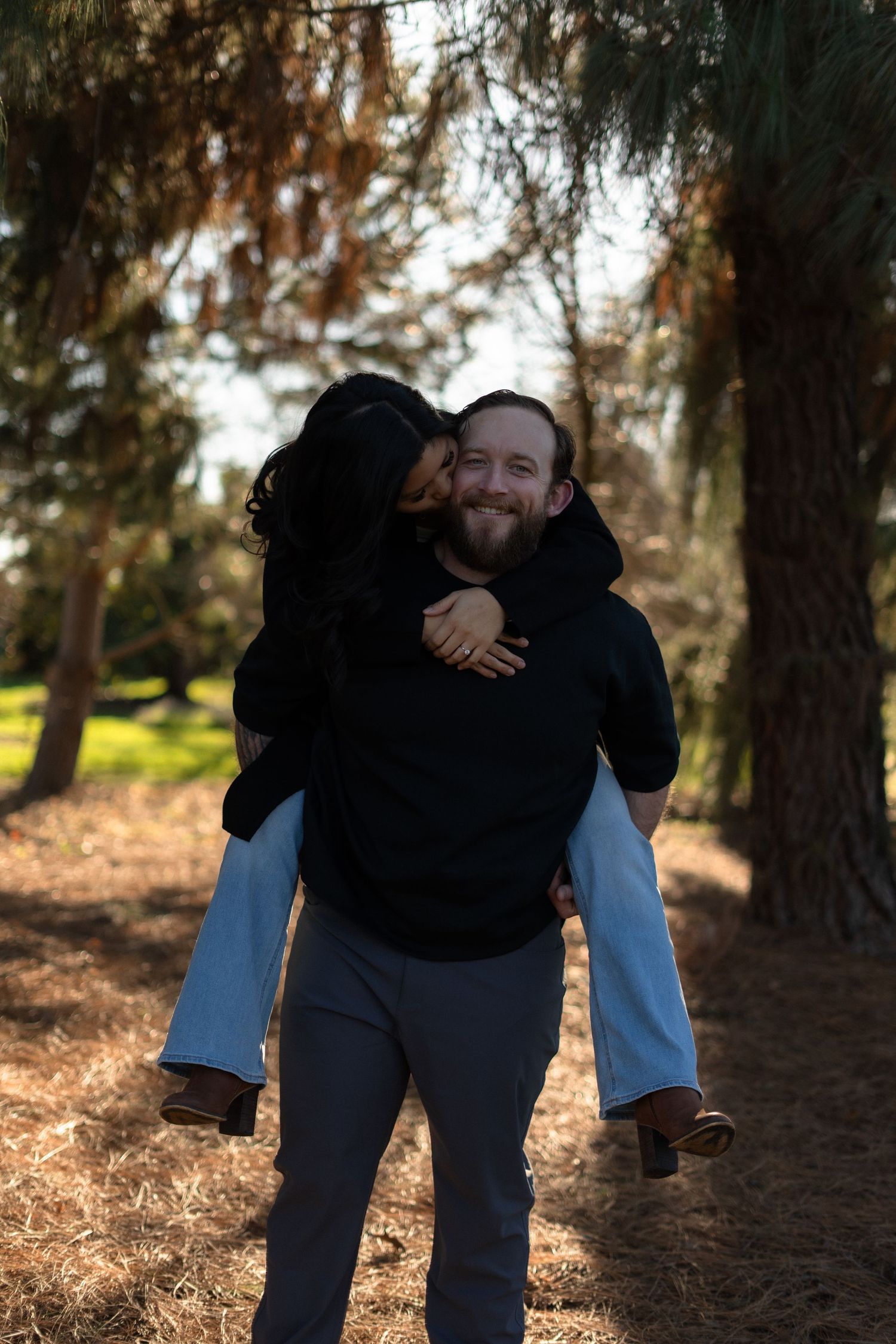 Playful piggyback ride through a wooded area on a sunny afternoon.