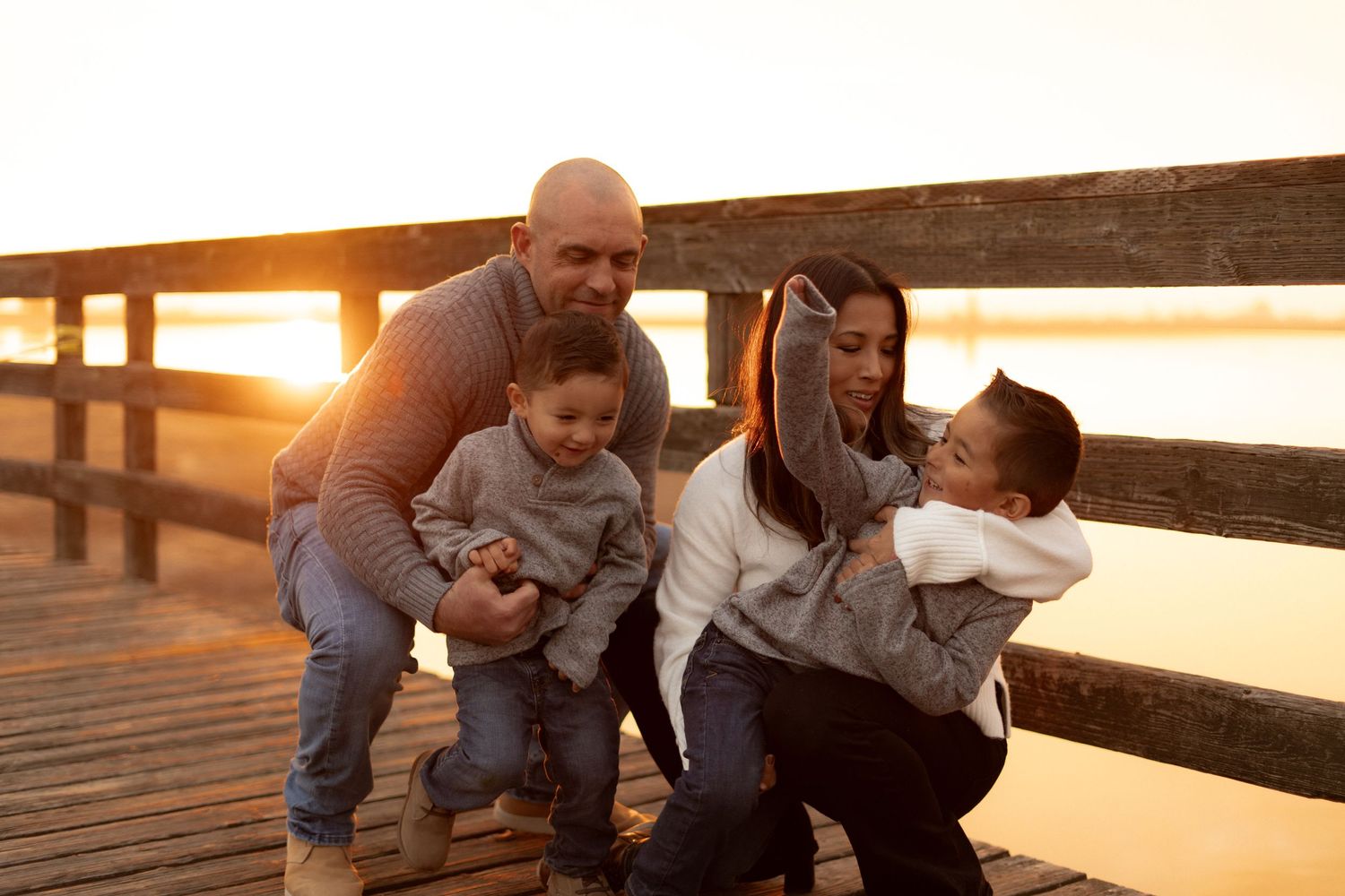 Two people embracing on a wooden deck during golden hour sunset.