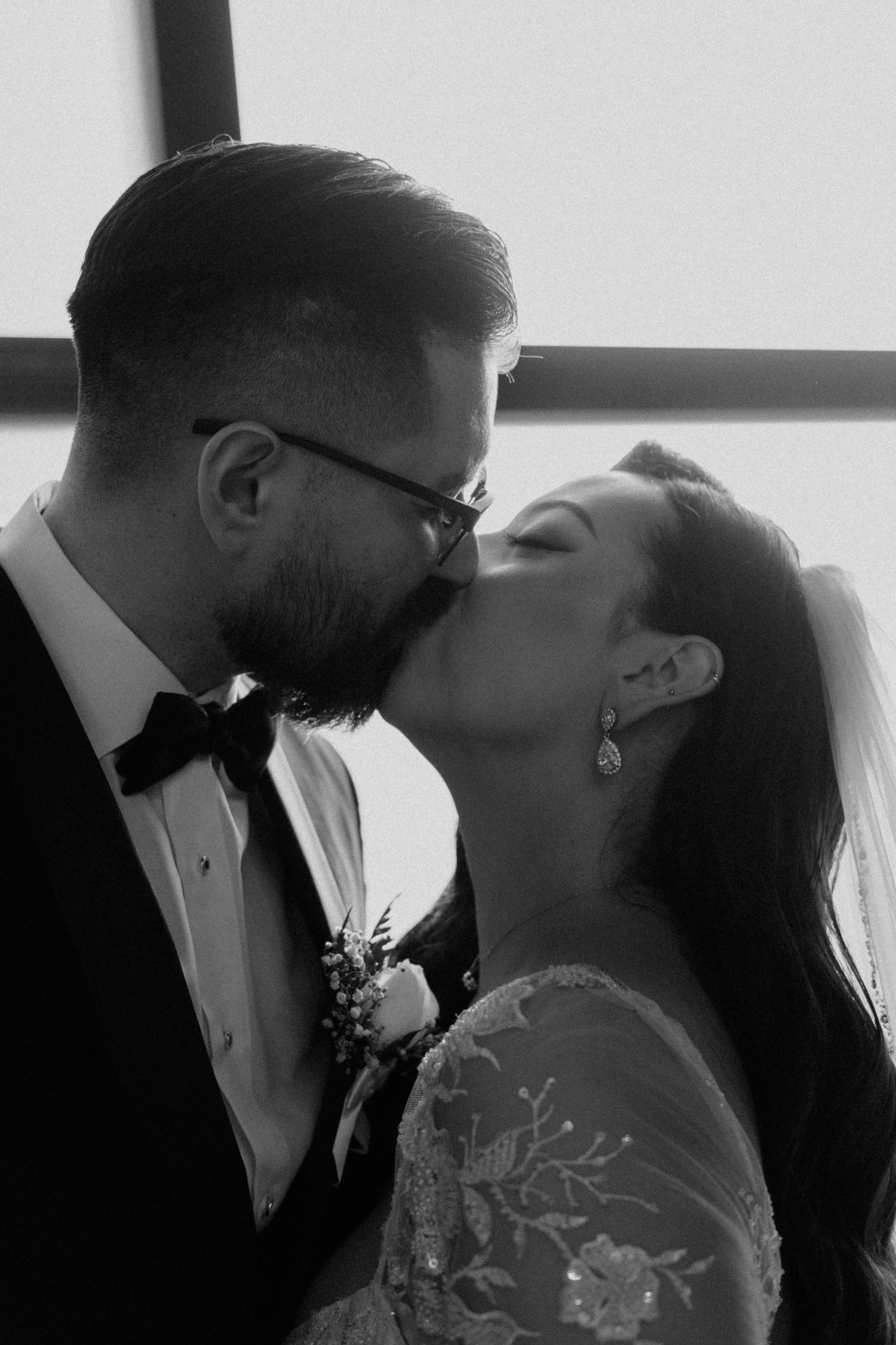 Romantic black and white portrait of a couple kissing during their wedding ceremony.
