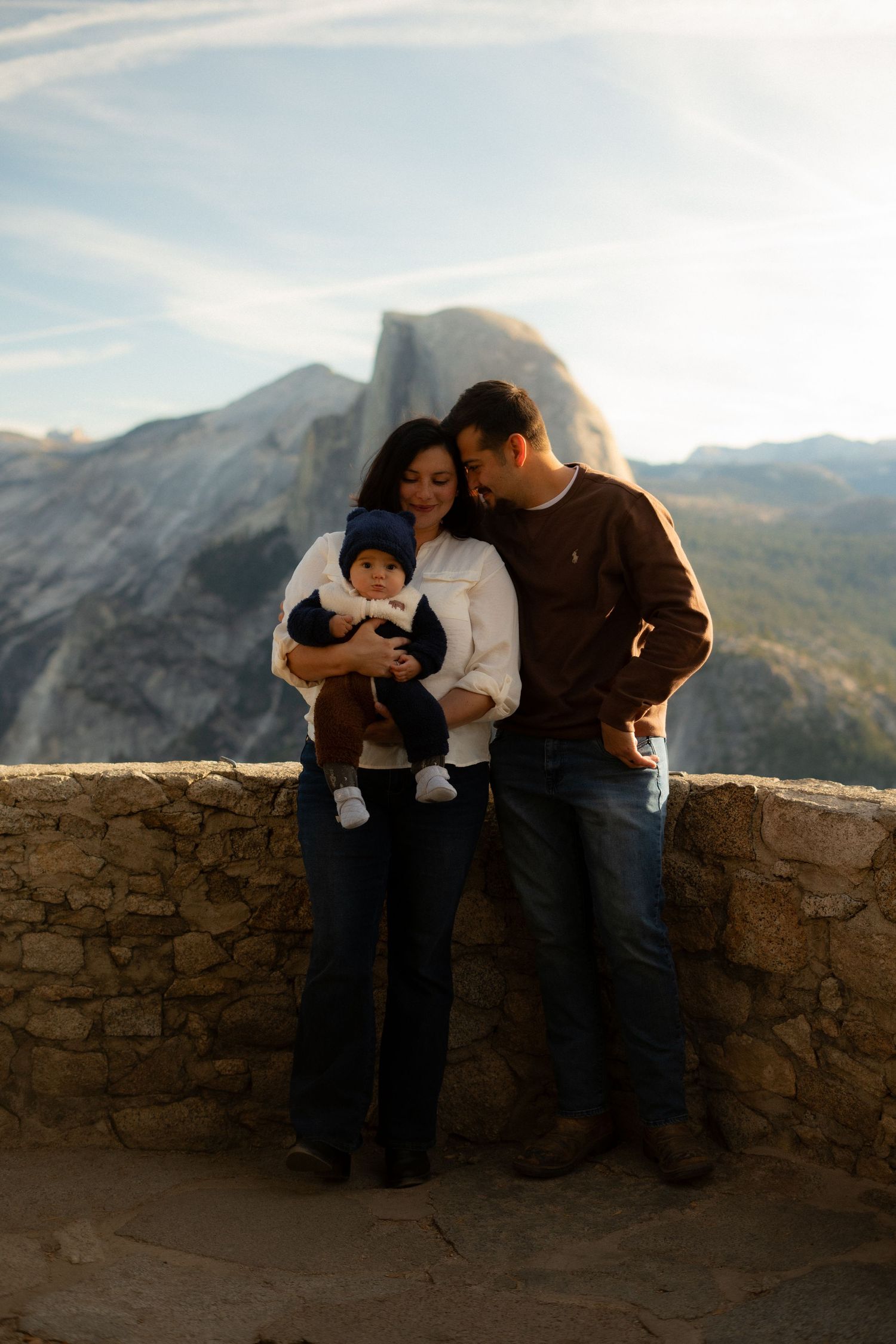 Family enjoying scenic mountain views together at stone overlook during sunset.
