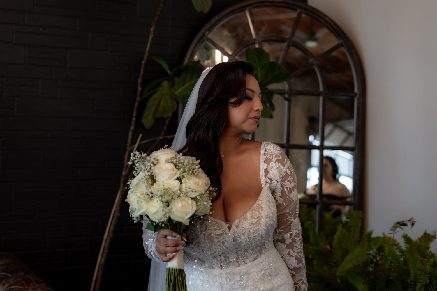 Elegant bridal portrait with white bouquet against arched mirror backdrop.