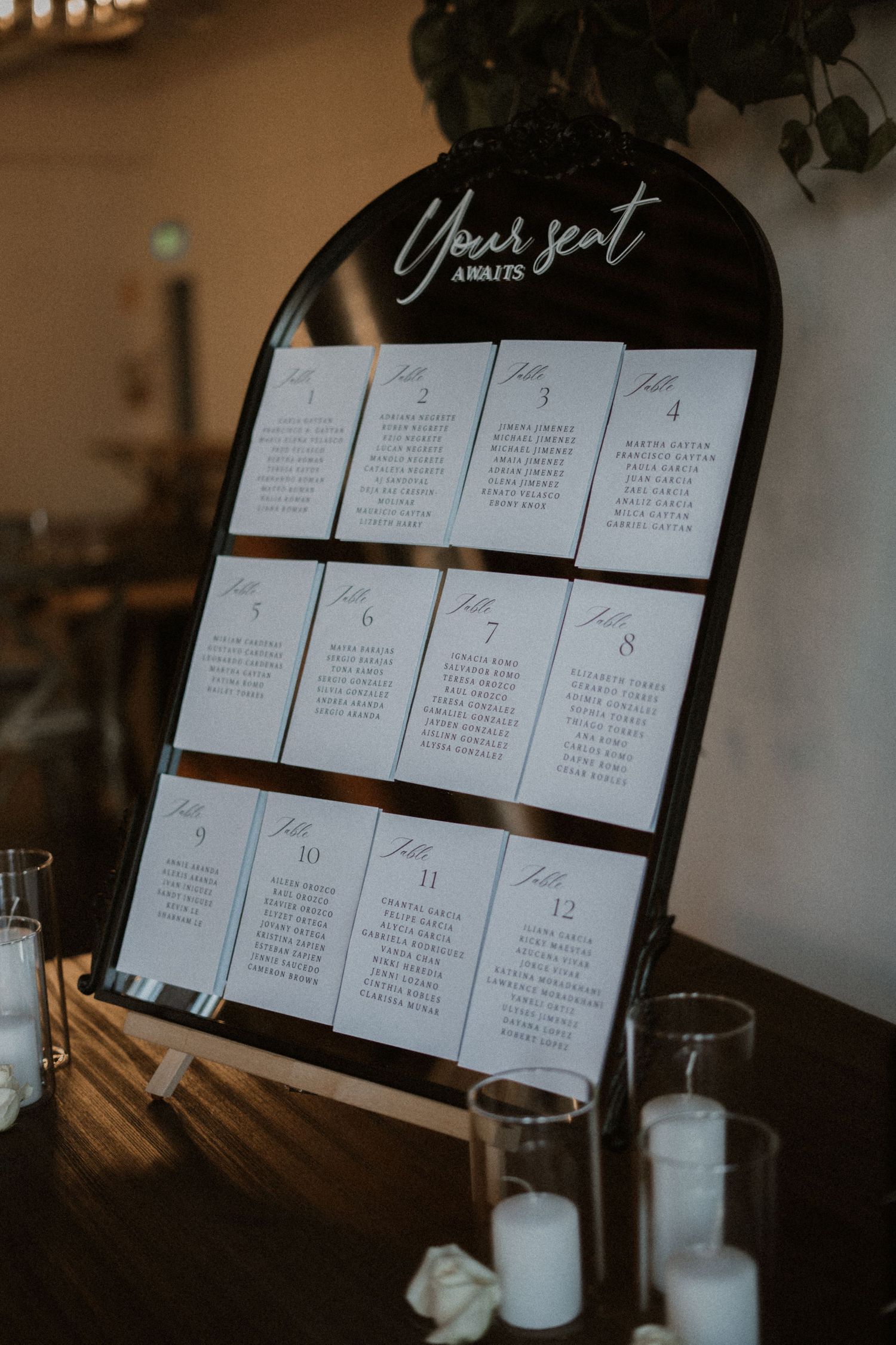 Wedding seating chart displayed on black board with white cards arranged in numbered grid format.
