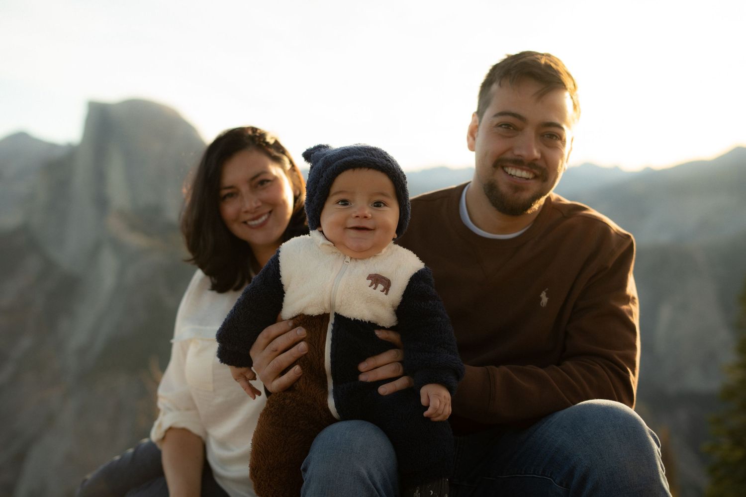 Family poses together on mountain overlook during golden hour.