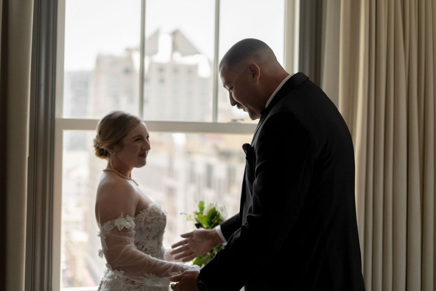 A tender moment between a couple in formal attire by a window.
