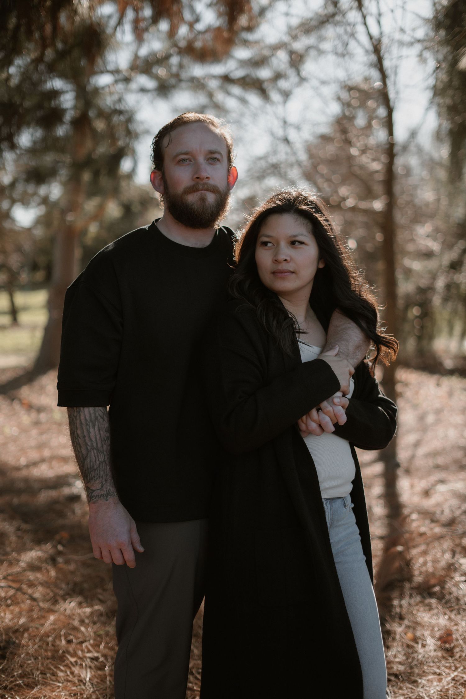 Couple in black clothing posing for moody forest portraits.