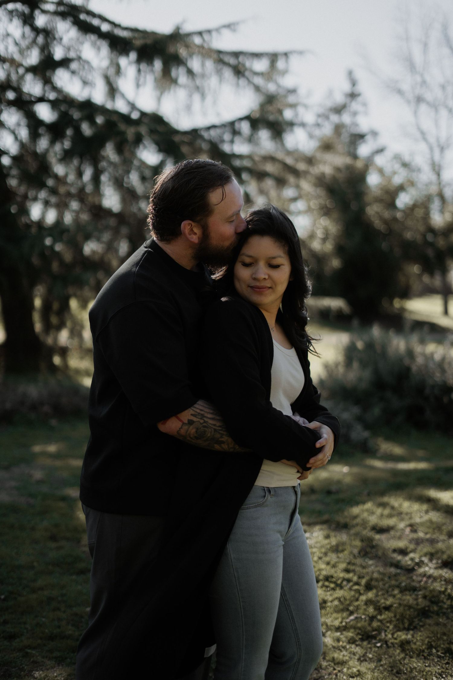 Romantic outdoor photoshoot featuring a couple among evergreen trees.