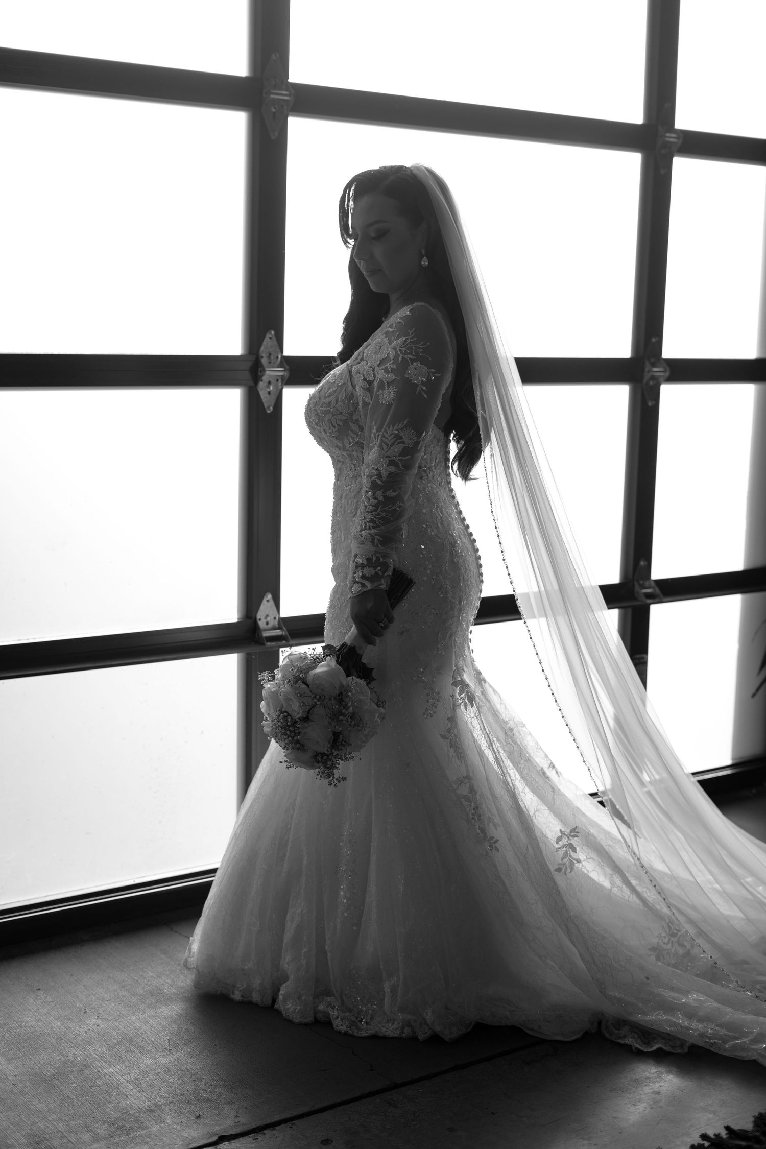 Silhouette of a bride in a flowing wedding gown with dramatic backlighting creating an ethereal effect.