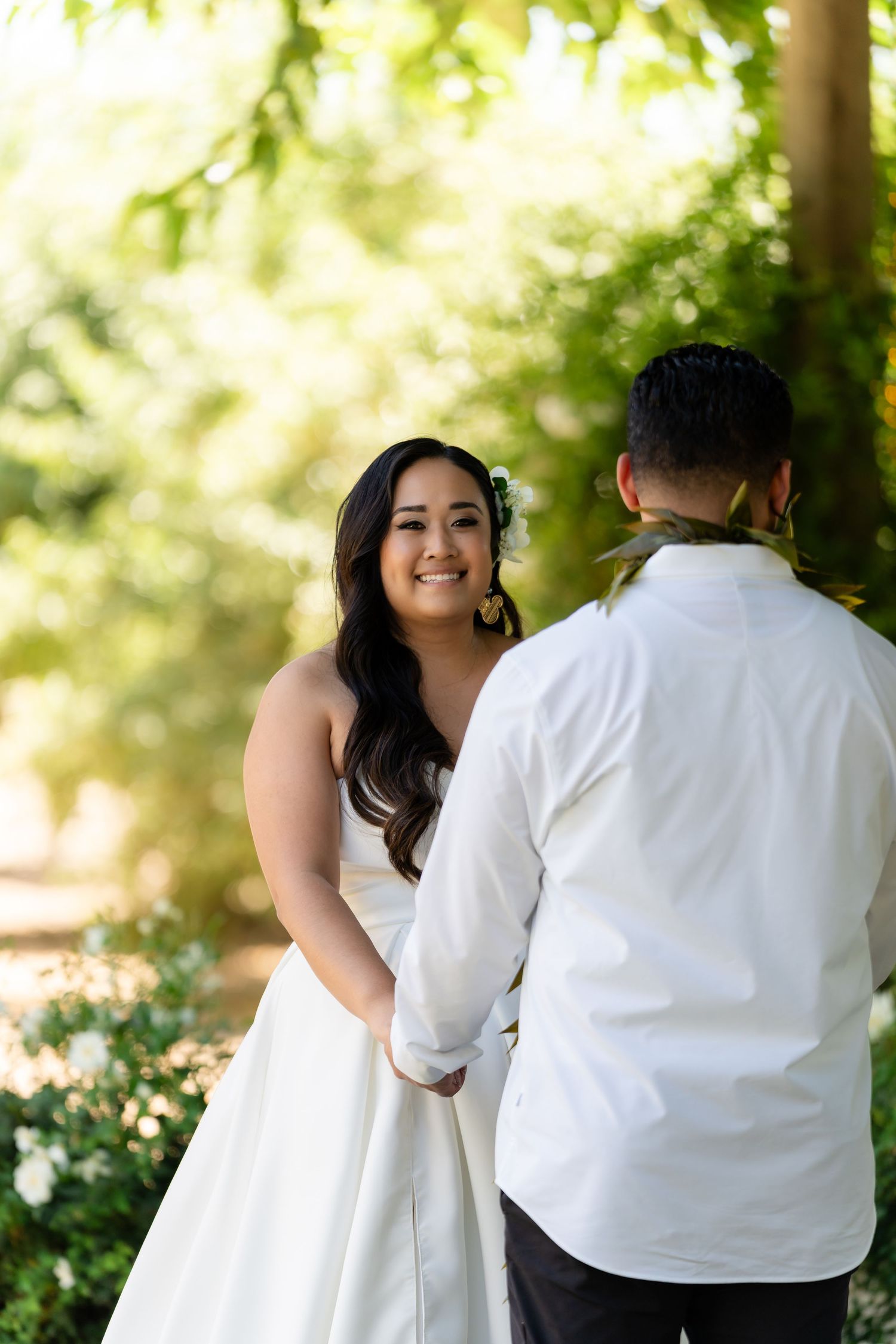 A couple shares a tender moment in a garden setting with soft natural lighting and greenery in the background.