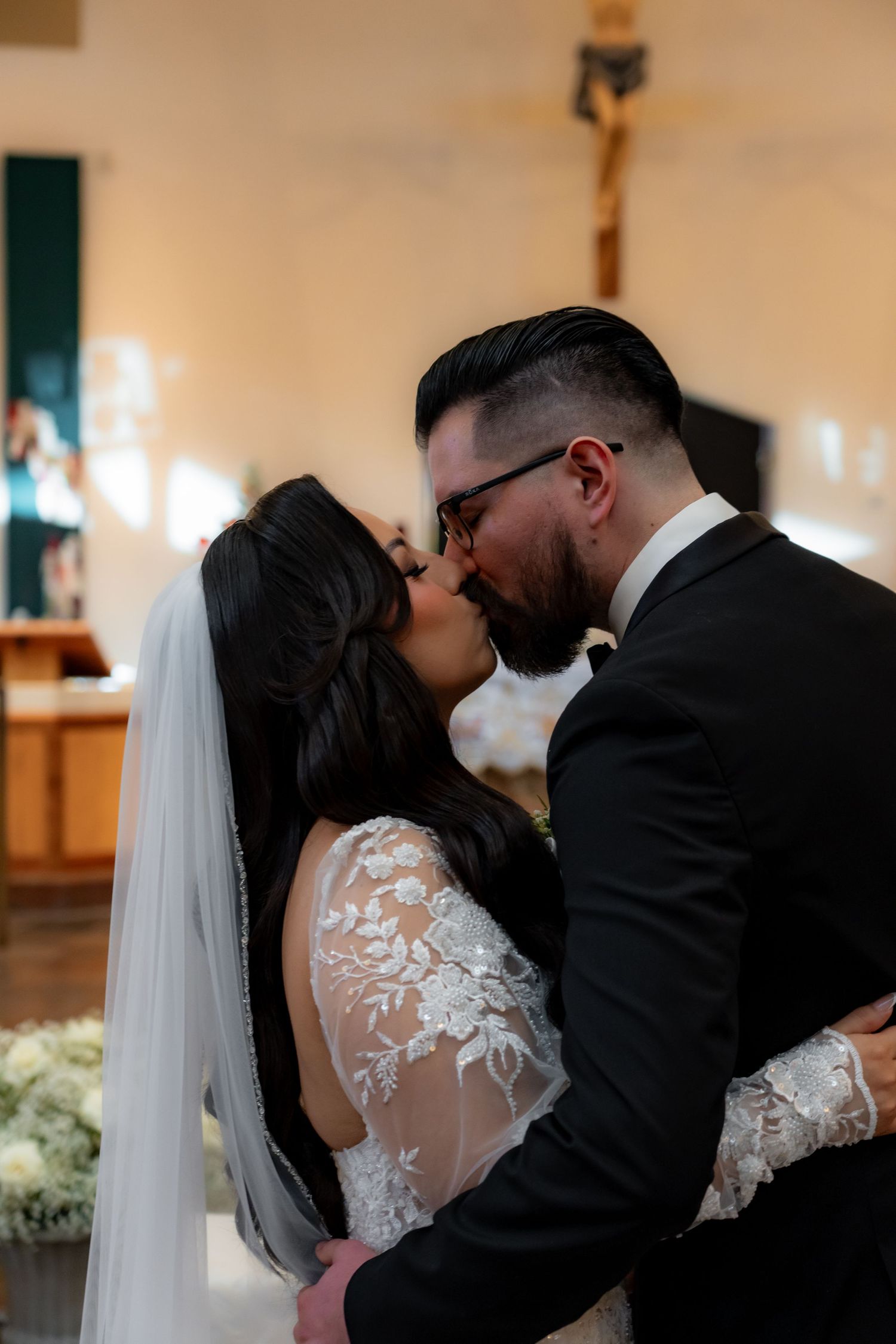 Newlyweds share their first kiss during intimate church wedding ceremony.