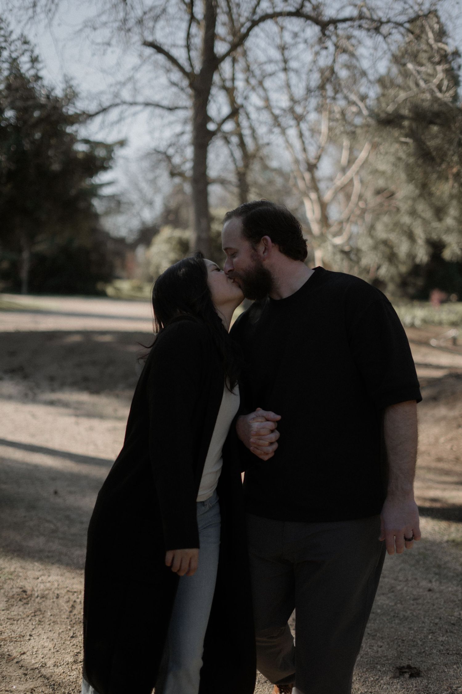 A tender moment between a couple sharing a kiss on a nature path.