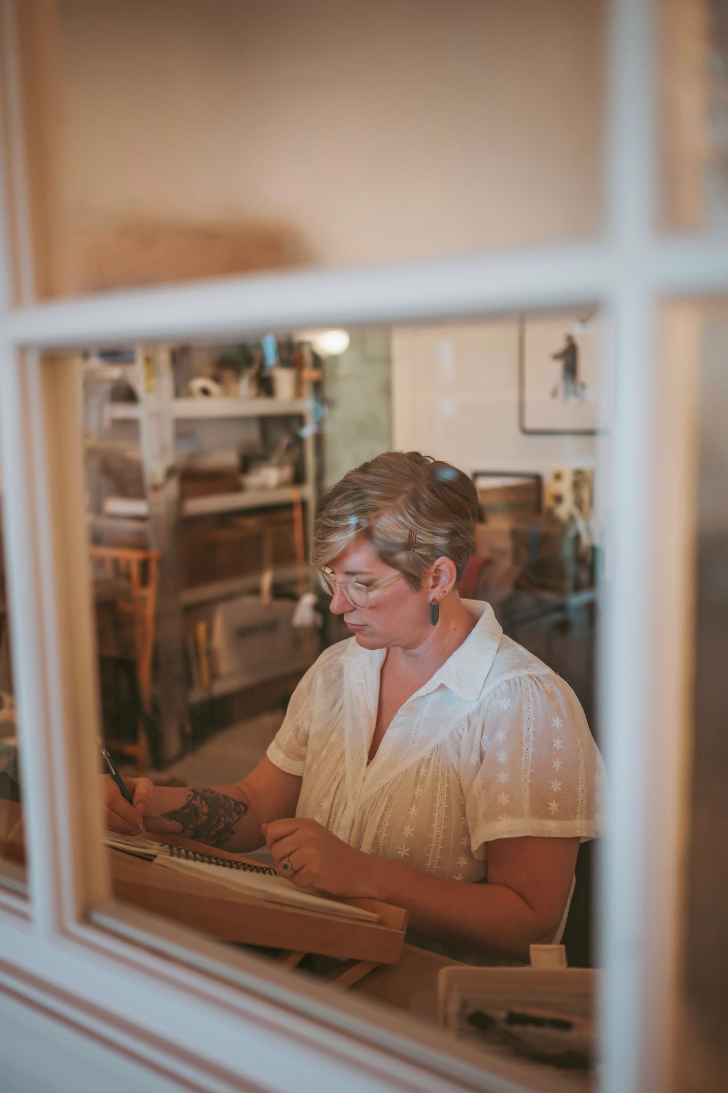 A series of vintage photos showing someone working at a desk through window frames in a sepia-toned setting.