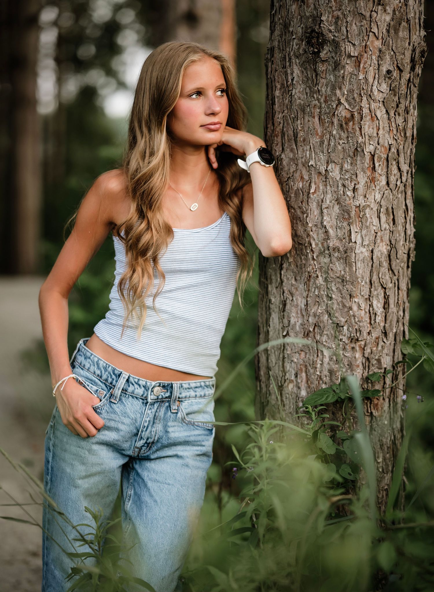 Casual summer portrait session in a wooded setting featuring light denim and a white tank top.