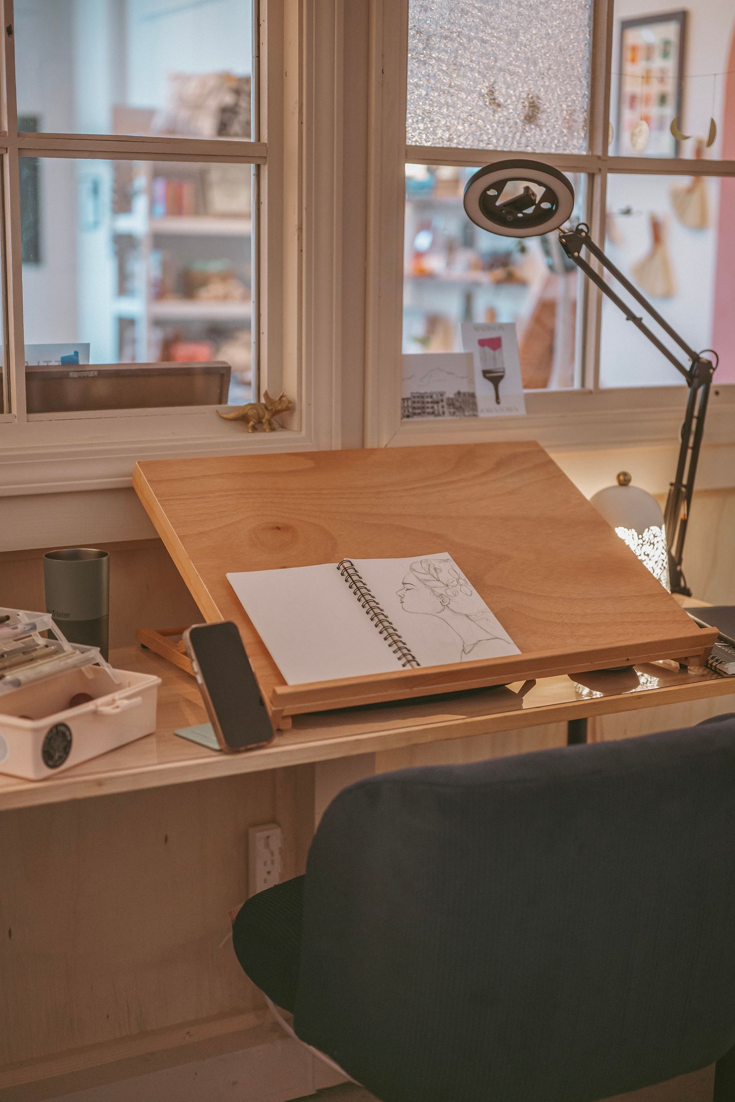 Wooden drafting desk with adjustable angle surface and task lamp in bright studio workspace.