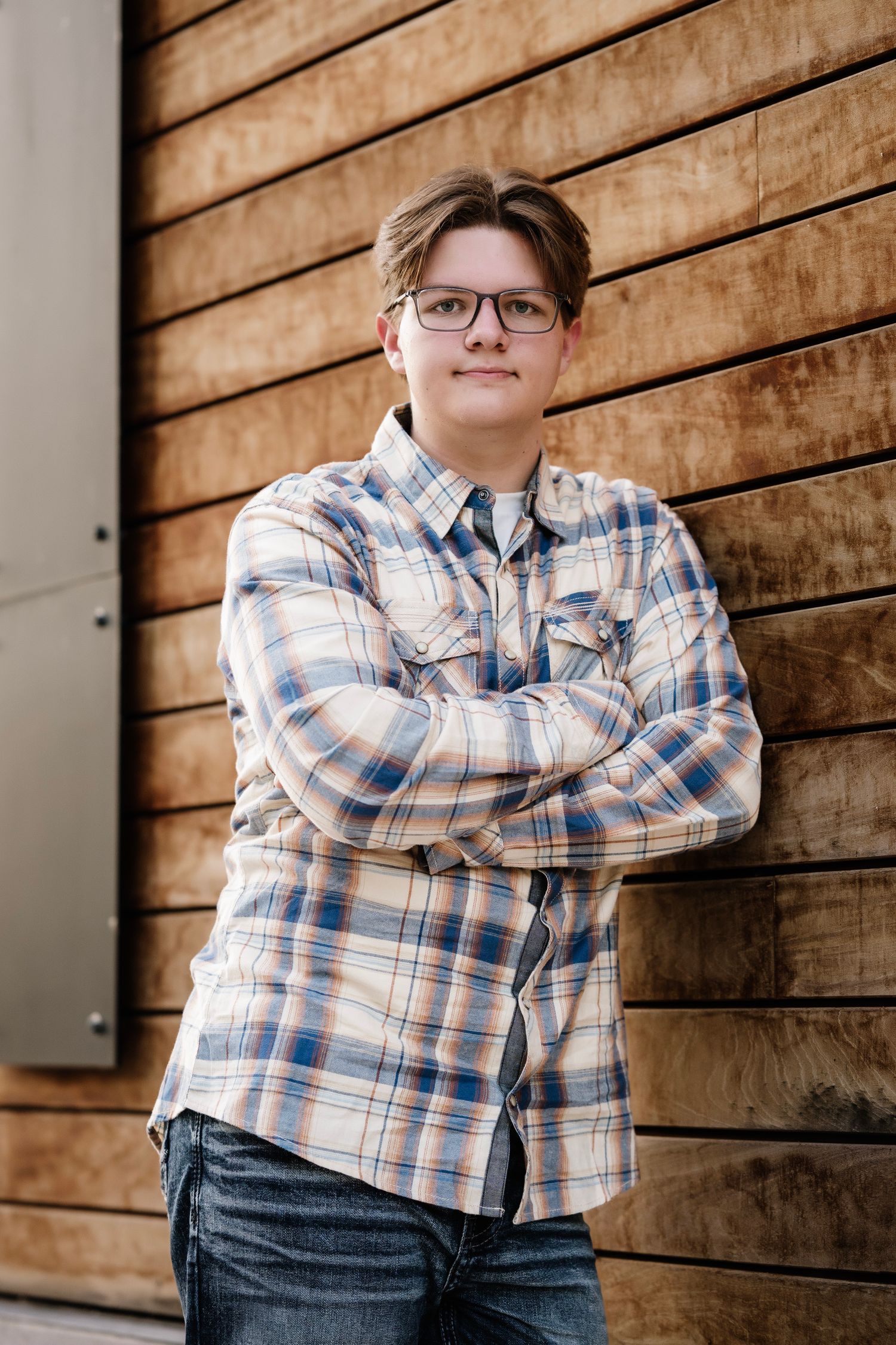 Person in plaid shirt and glasses poses against rustic wooden wall in series of cropped portrait shots.