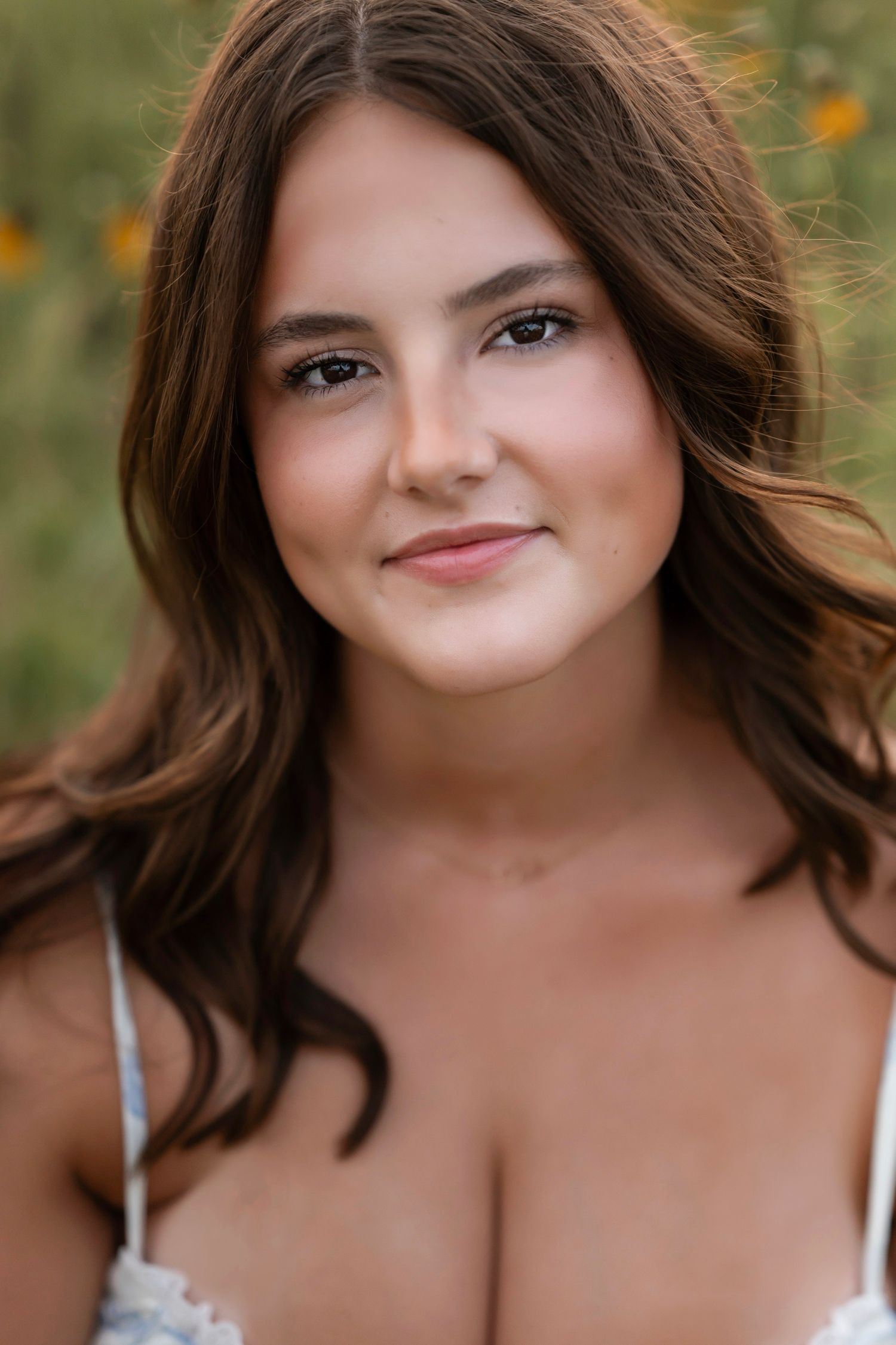 Portrait photo against blurred natural background with warm lighting and soft bokeh effect.
