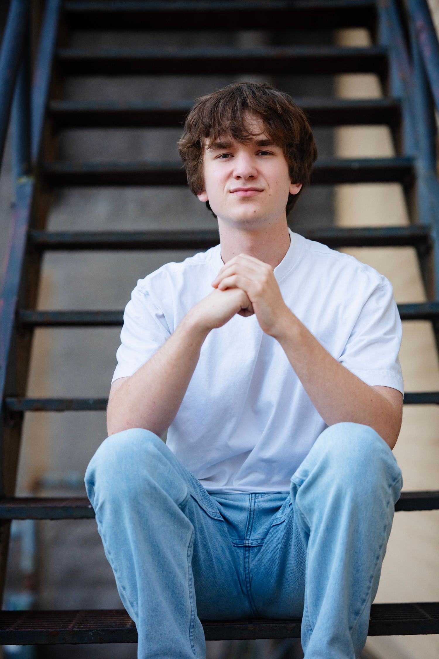 A person in a white shirt and light blue jeans sits thoughtfully on dark wooden stairs in a series of similar poses.