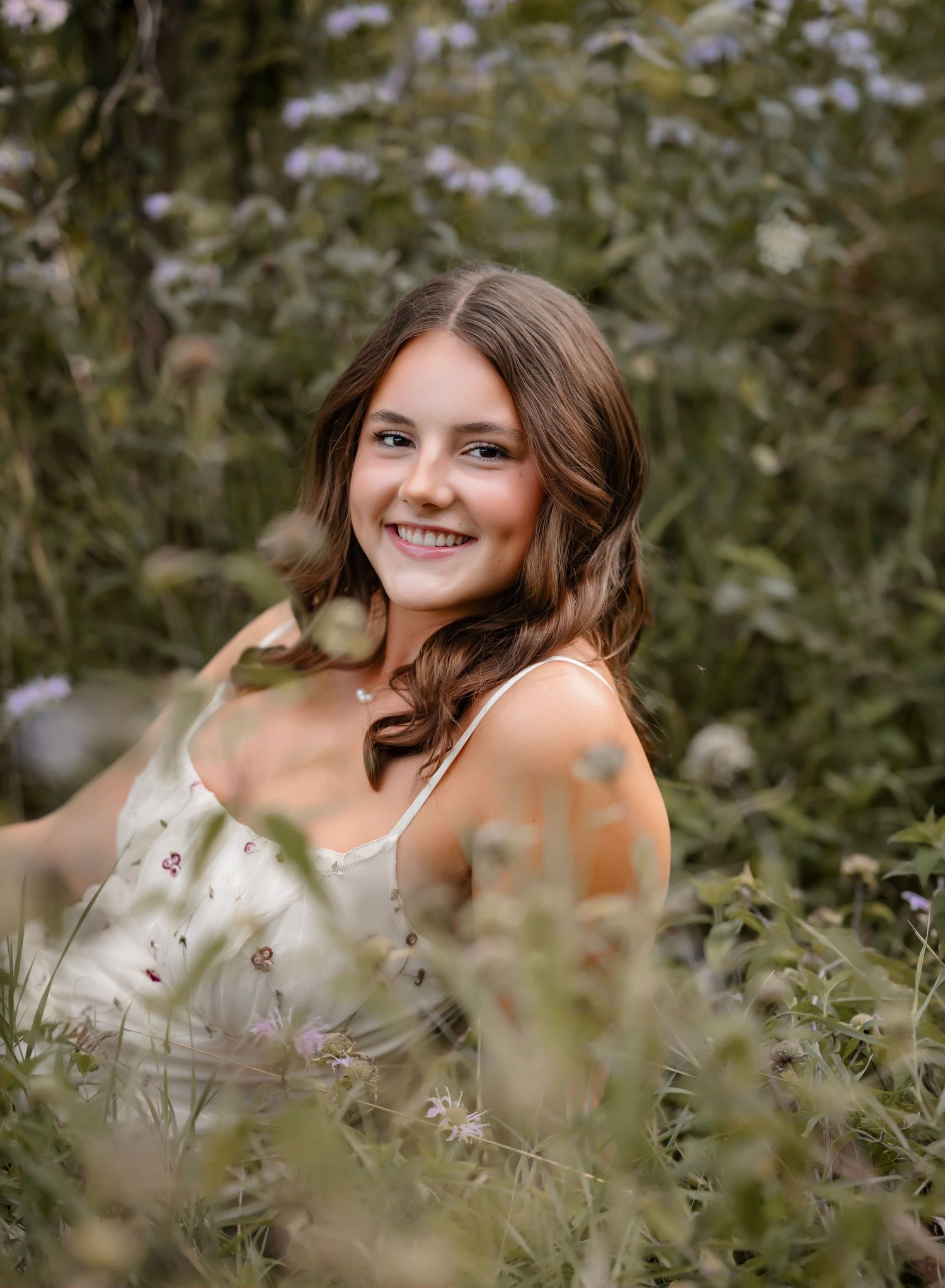 A joyful figure poses in a field of delicate white wildflowers during a golden hour photoshoot.