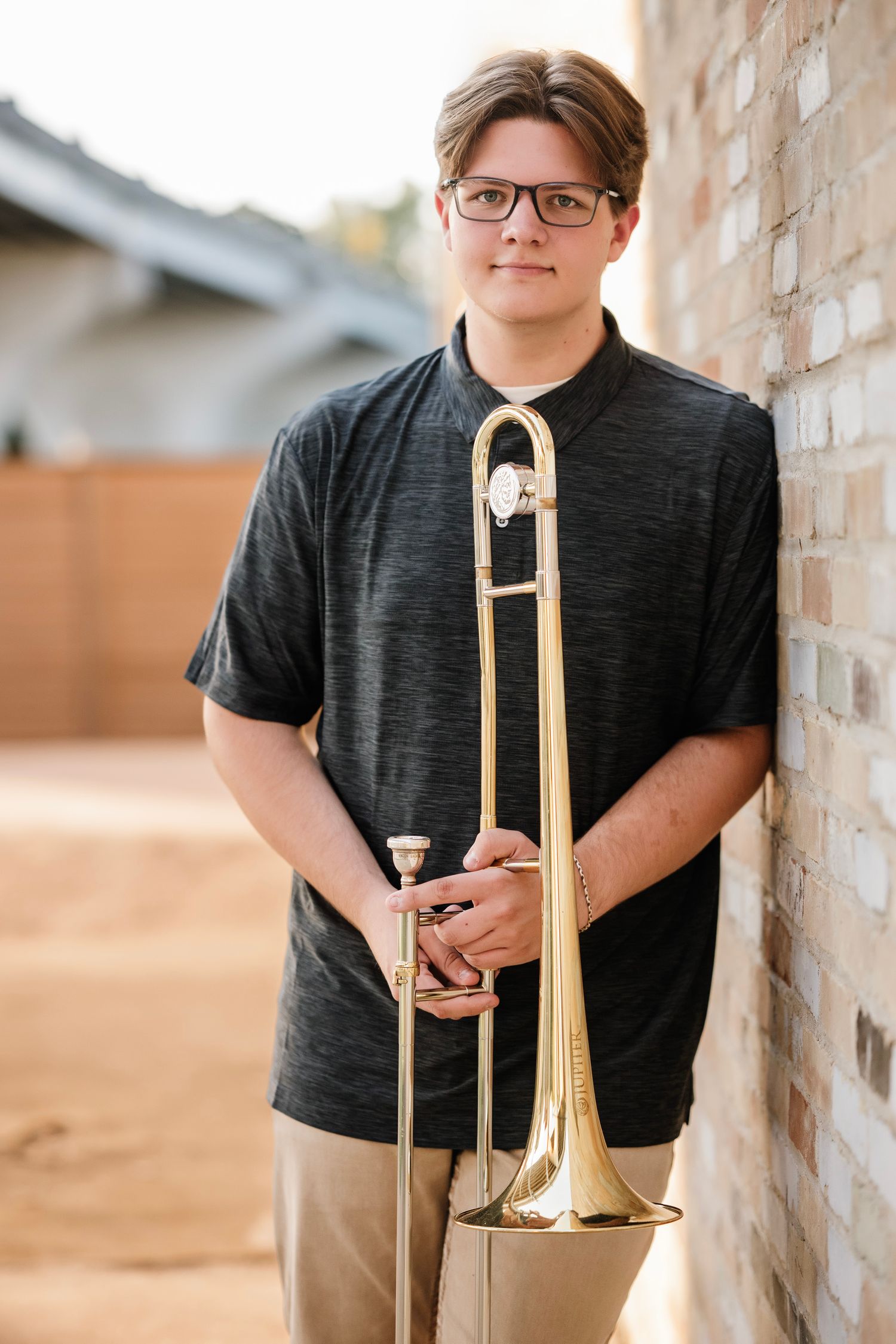 A series of portraits showing a student musician with a brass trombone against a brick wall background.