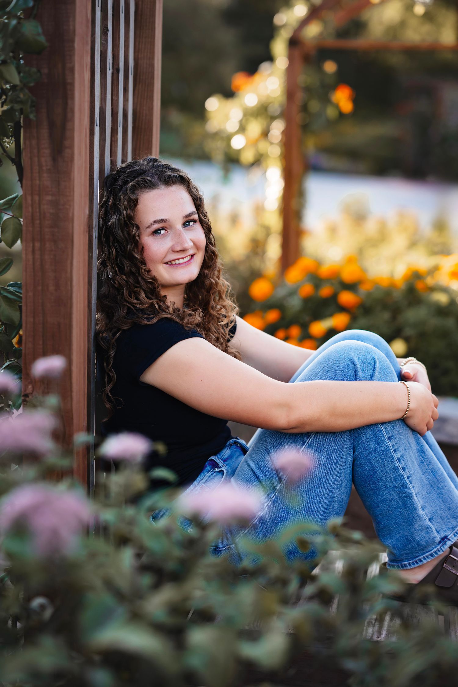 A casual outdoor portrait session in a garden with blooming flowers and natural lighting at golden hour.