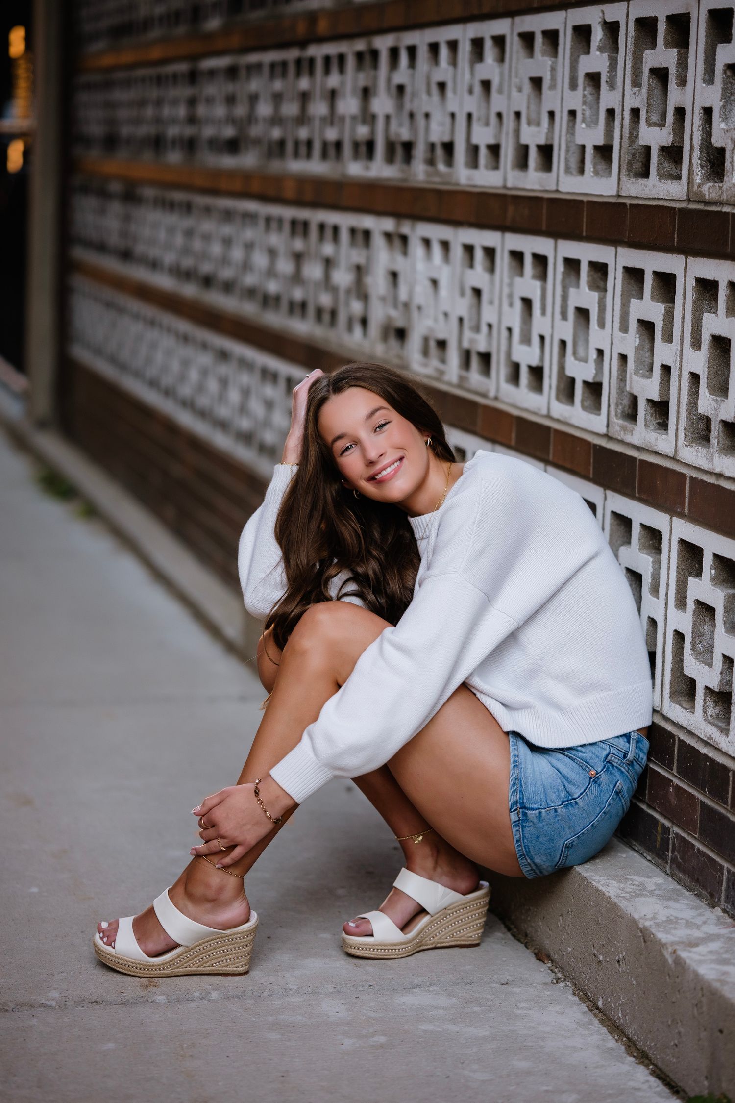 A series of artistic portrait photos showing someone in casual summer attire sitting against a decorative wall.