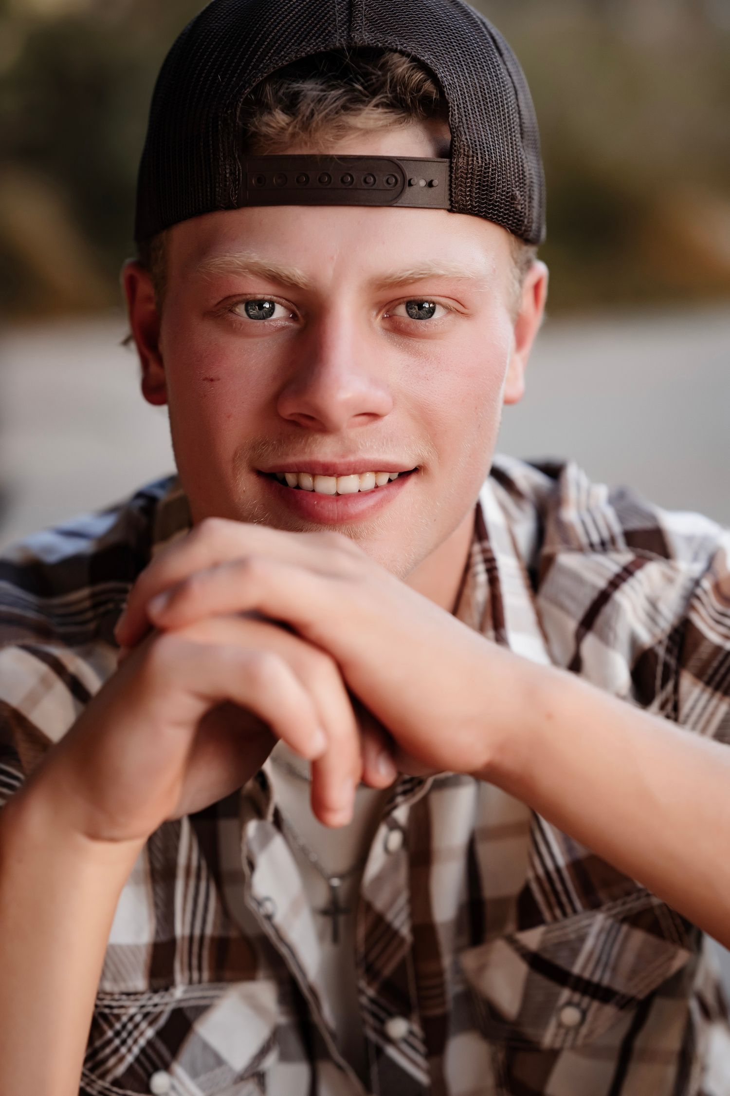 A series of four close-up portraits showing someone wearing a plaid shirt and baseball cap with varying expressions.
